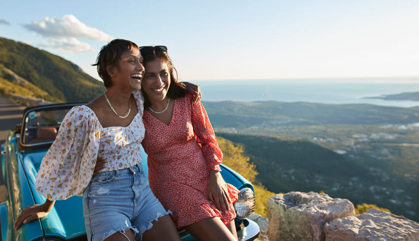two women sitting on a car outside