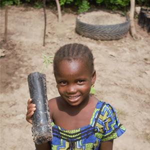 young girl holds a seedling to be planted as part of the Forest for the Future Initiative to grow sustainable Forest Garden Projects in Koungheul, Senegal.