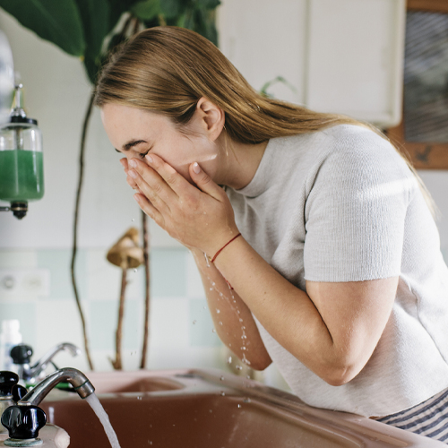 A woman washing her face with water.