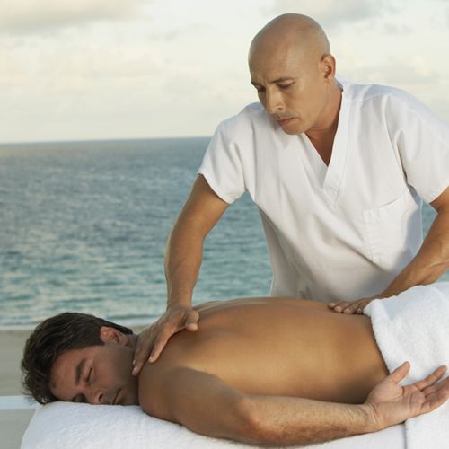 A man receives a back massage in an ocean view setting