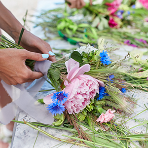 A woman wraps stems of wildflower bouquet