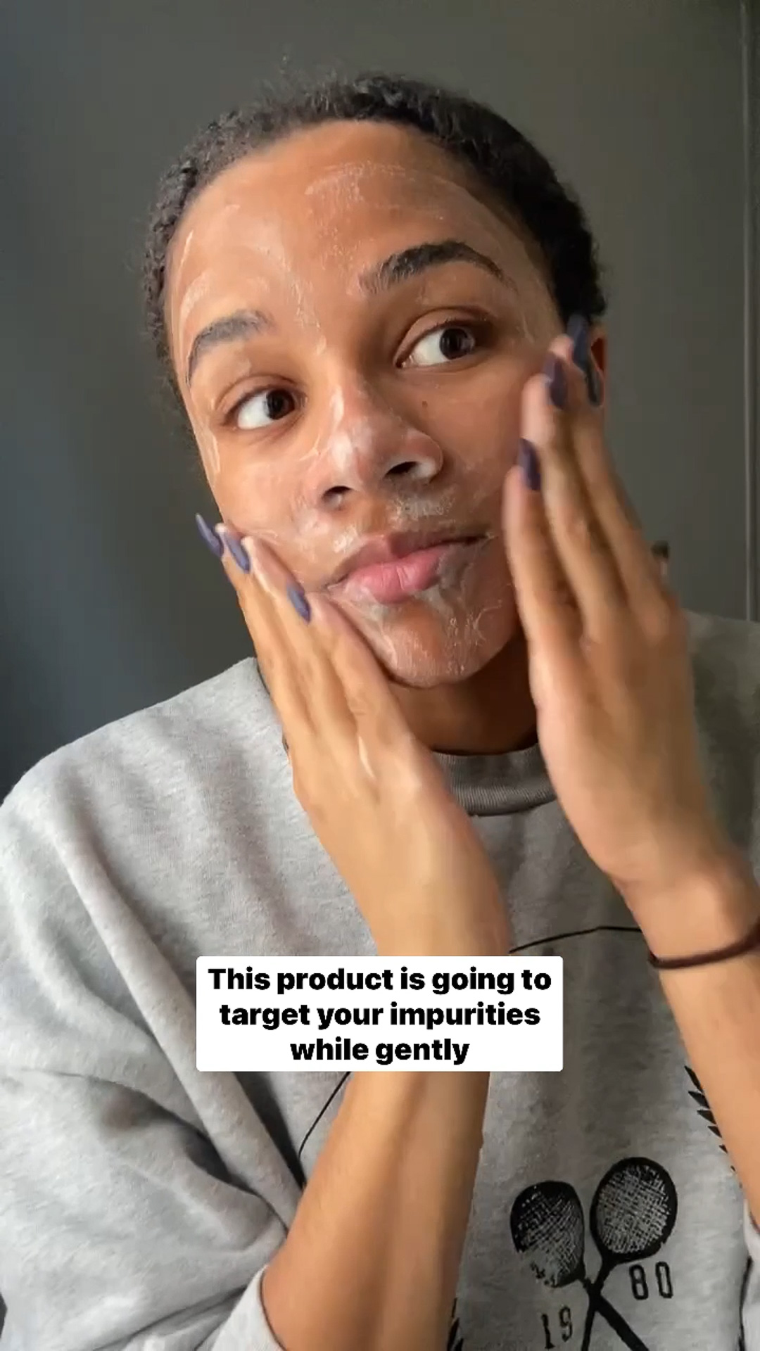 A woman applying Eminence Organics Charcoal Exfoliating Gel Cleanser to face