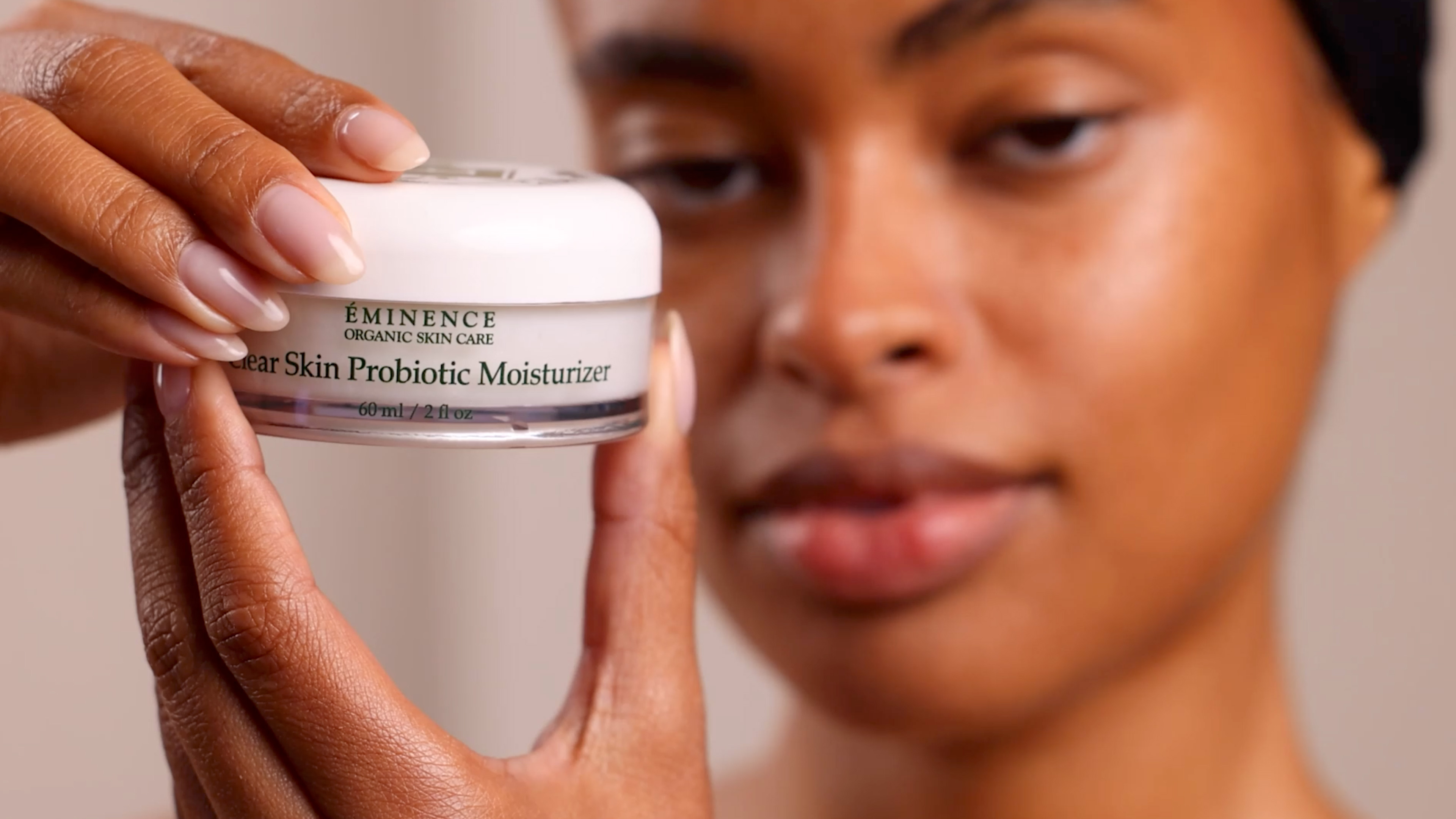 A woman holding Eminence Organics Clear Skin Probiotic Moisturizer in hands