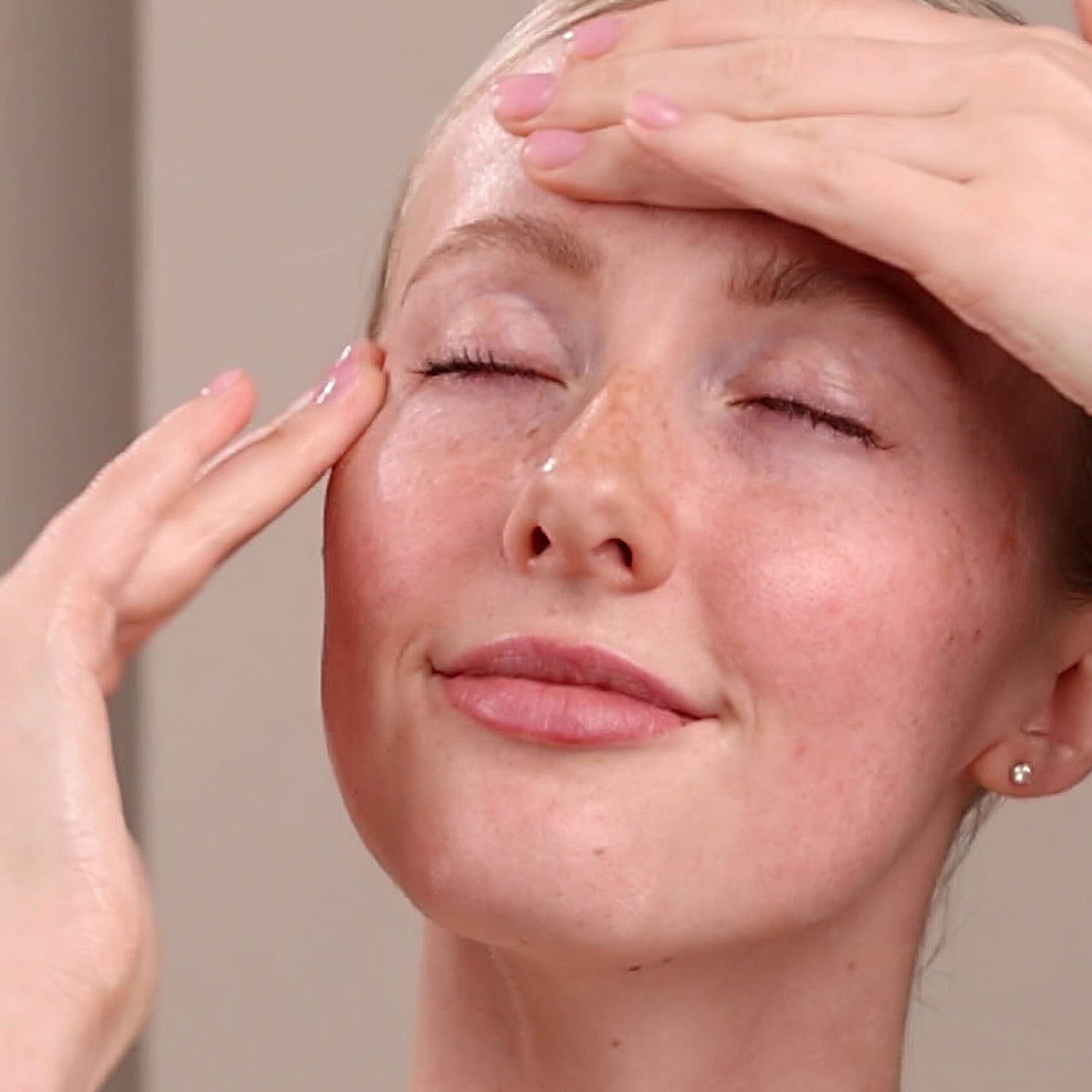 A woman applying the Eminence Organics Superfood Booster-Powder on her face