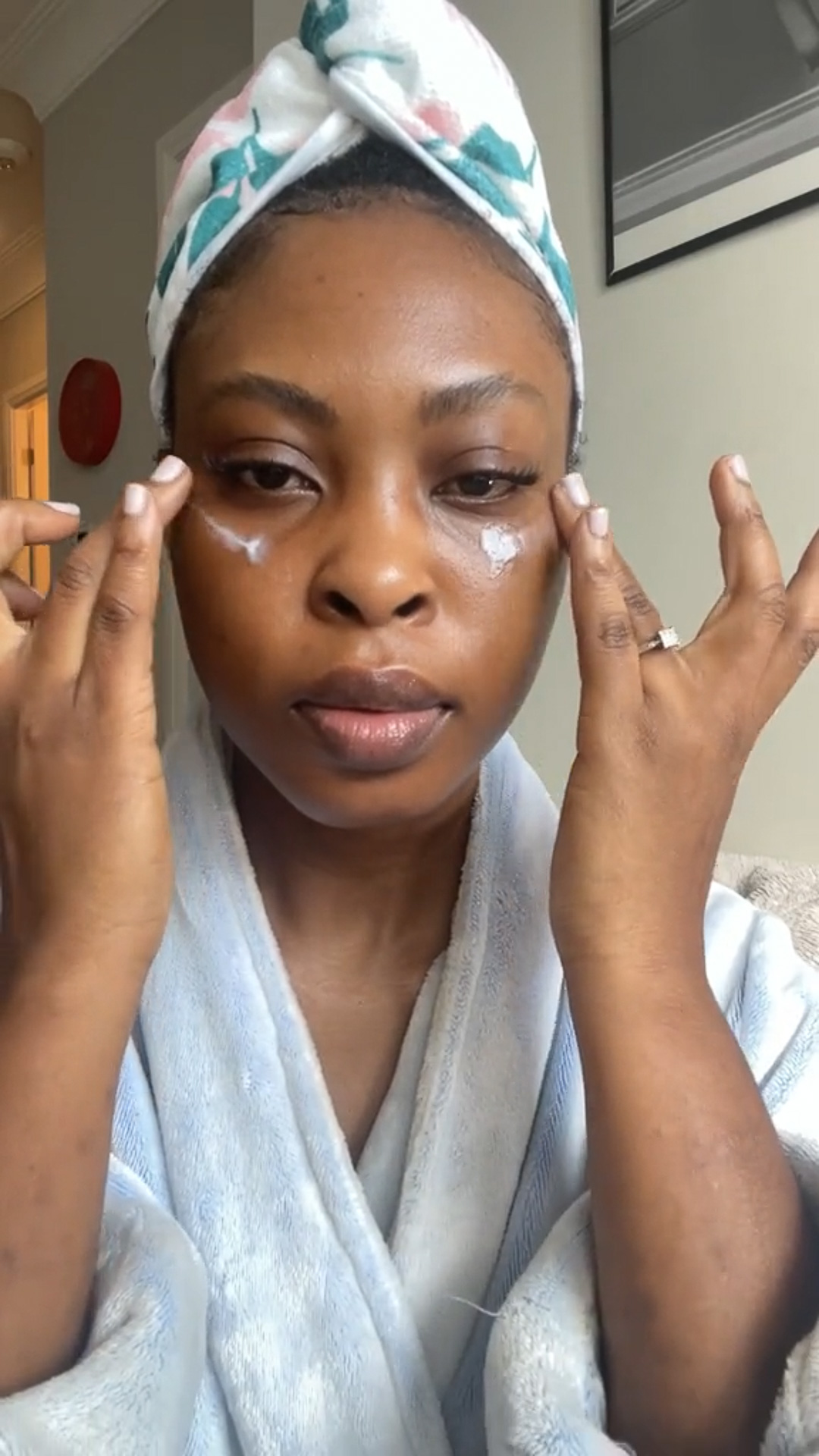 A woman applying the Eminence Organics Neroli Age Corrective Eye Serum to the eye area