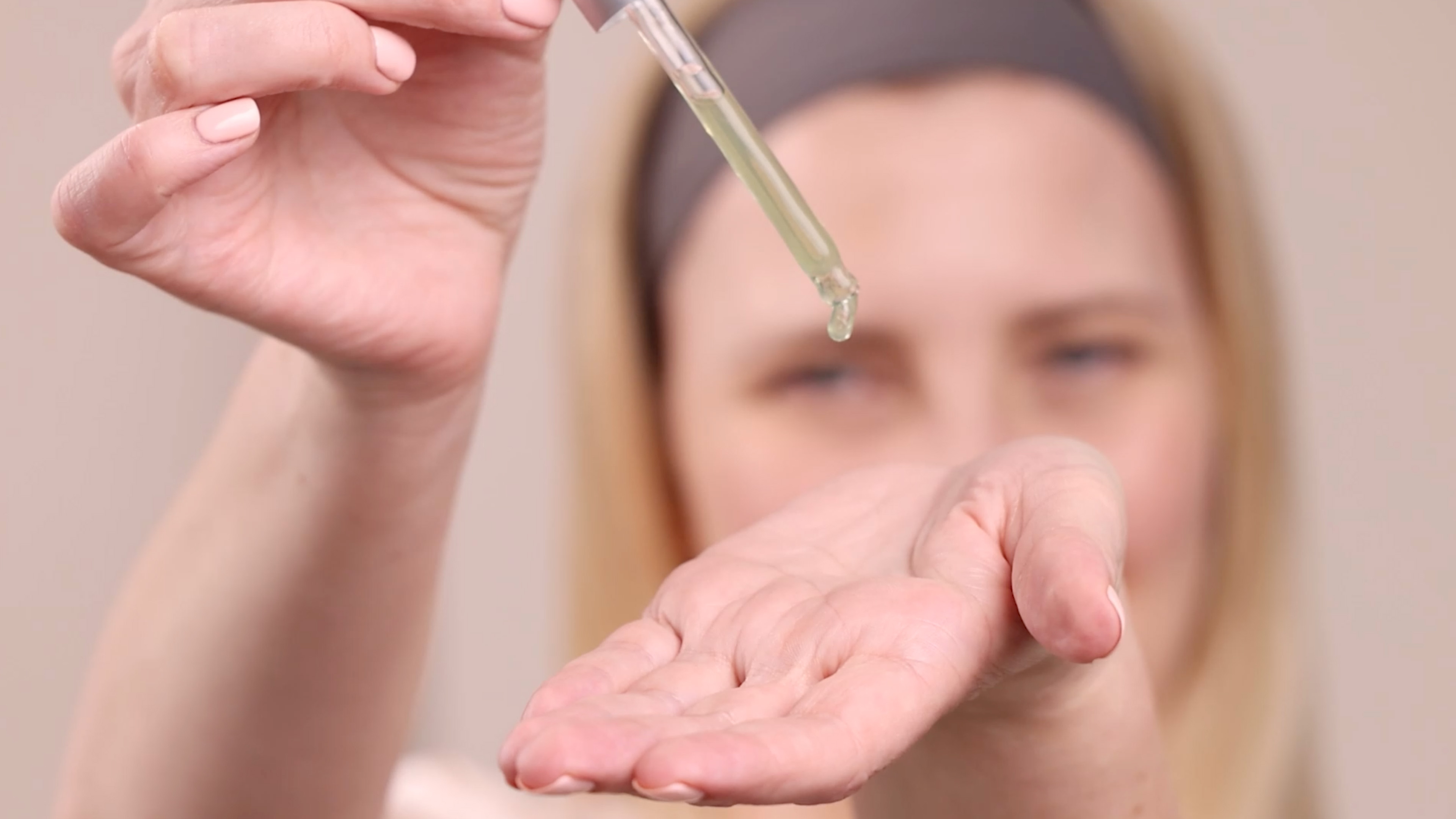 A woman applying Eminence Organics Bright Skin Licorice Root Booster-Serum to hand