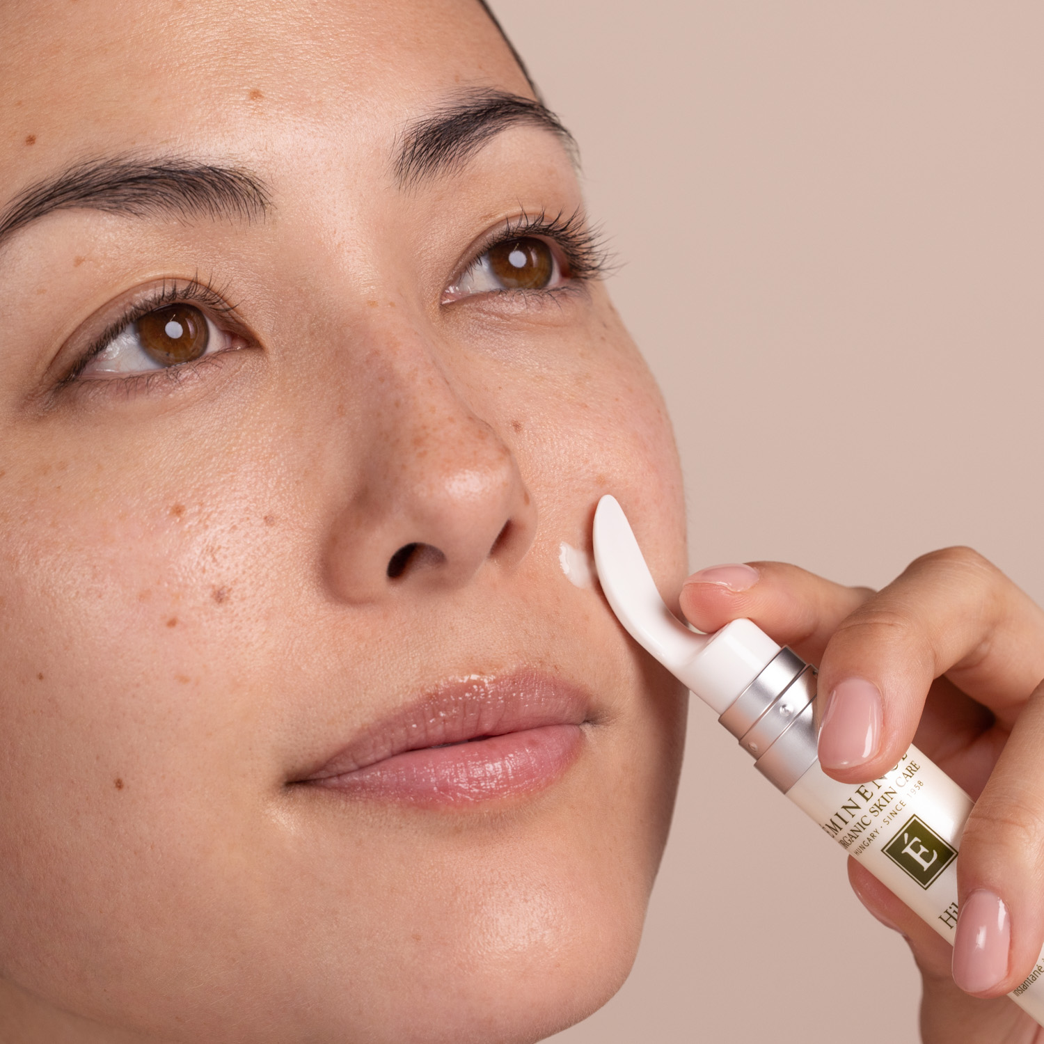A woman applying the Eminence Organics Hibiscus Instant Line Filler to her face