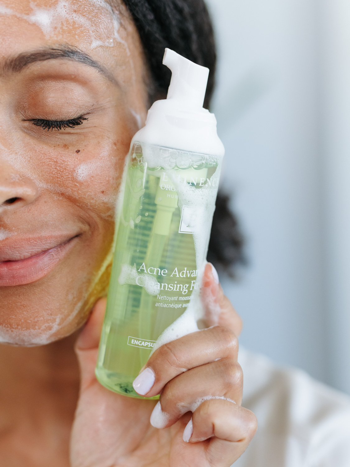 A woman holding Eminence Organics Acne Advanced Cleansing Foam