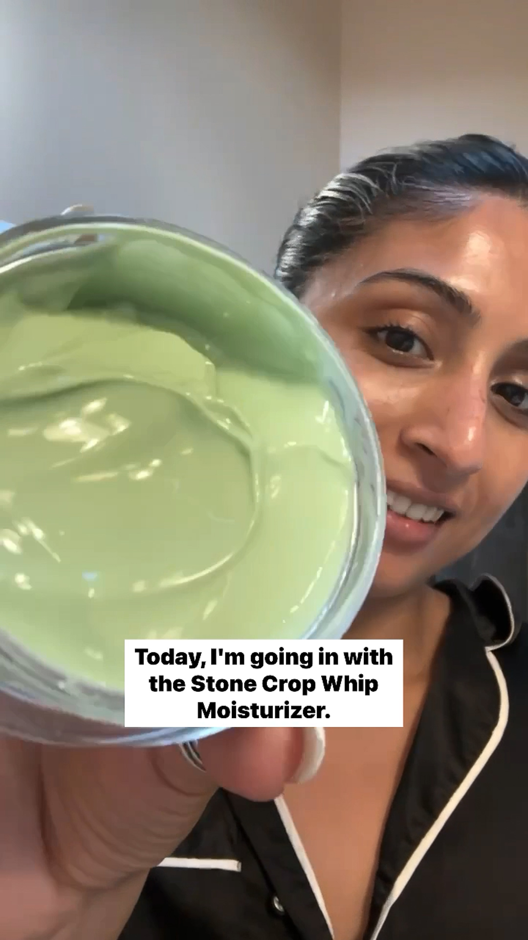 A woman holding an open jar of the Eminence Organics Stone Crop Whip Moisturizer