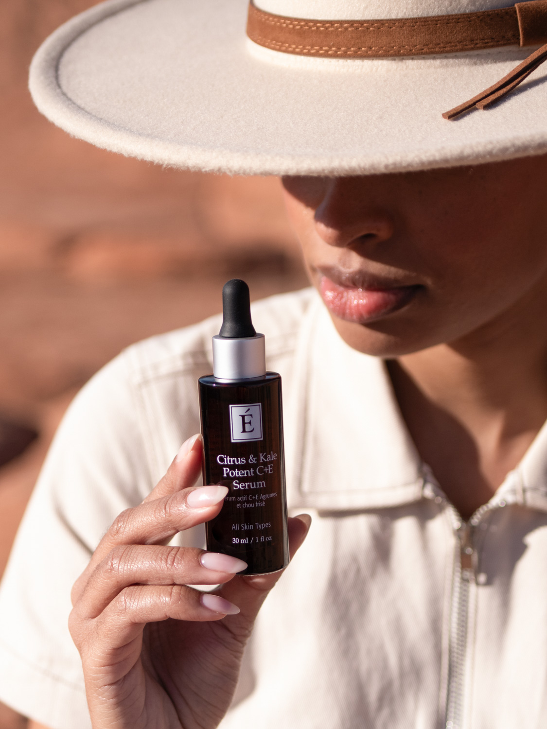 A woman holding Eminence Organics Citrus & Kale Potent C+E Serum