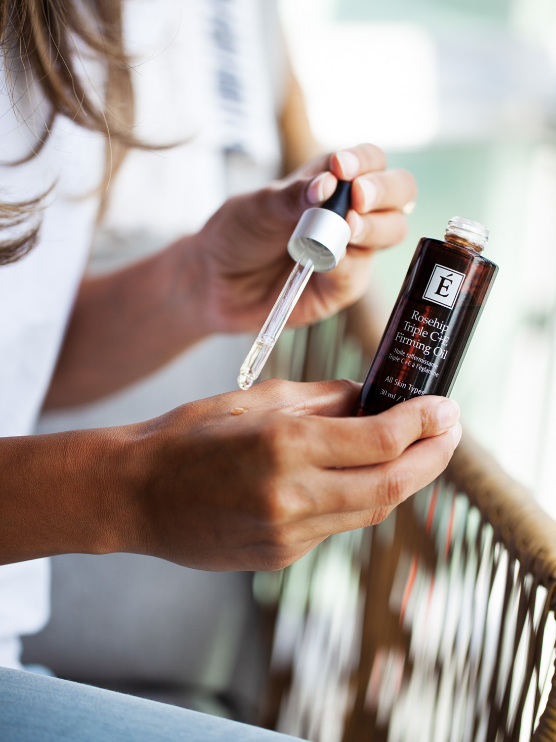 A woman holding the Eminence Organics Rosehip Triple C+E Firming Oil
