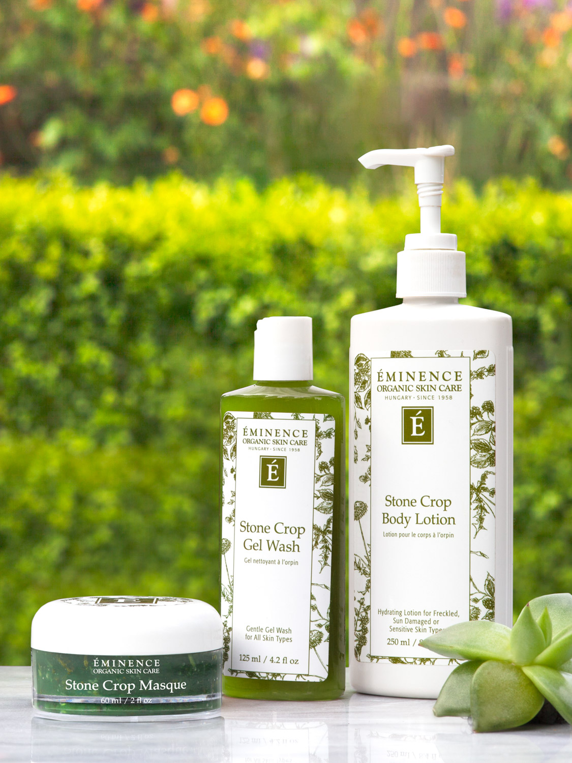 Eminence Organics Stone Crop Gel Wash next to other Eminence Organics products on a green outdoors background