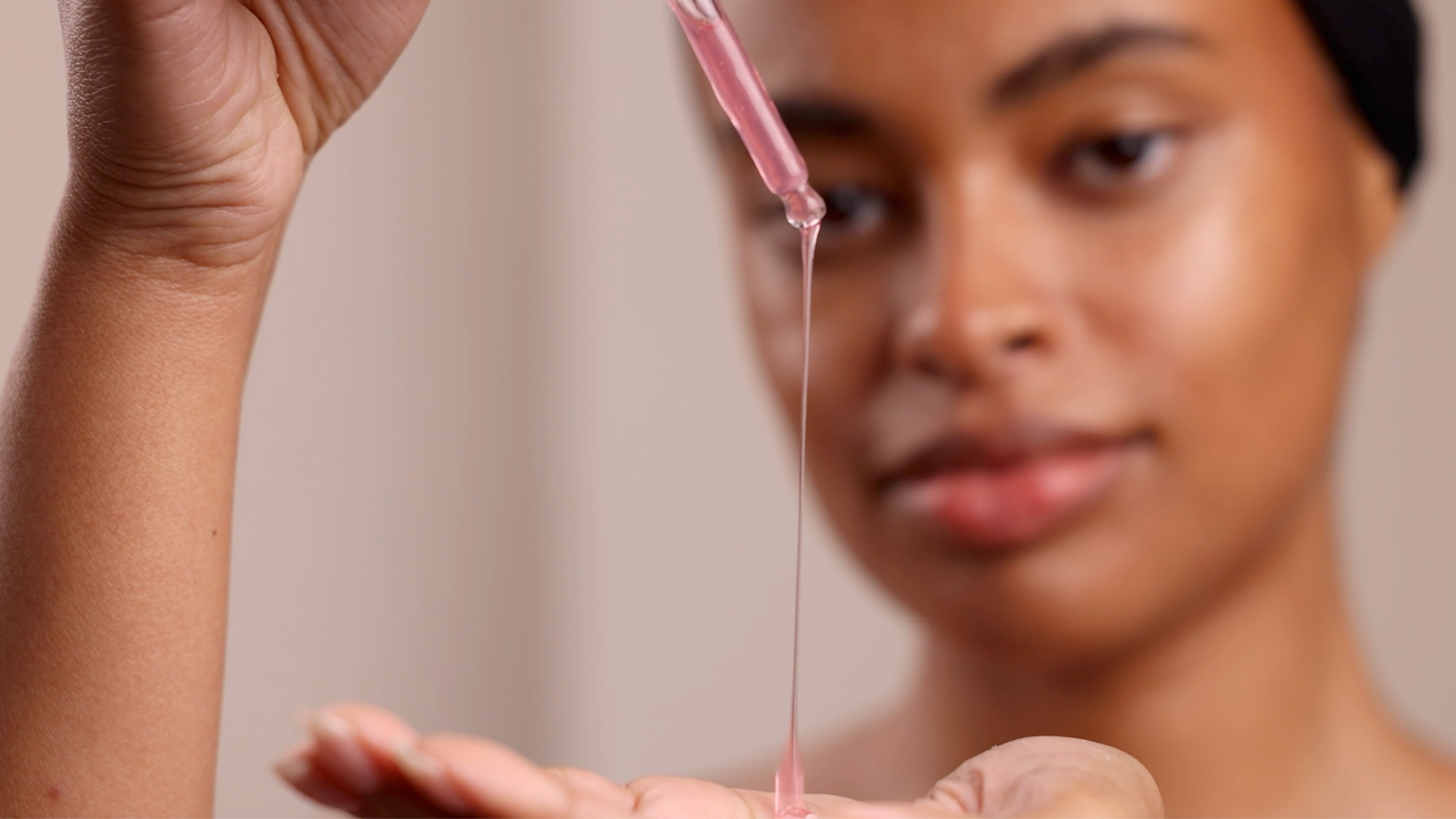 A woman holding a dropper filled with the Eminence Organics Strawberry Rhubarb Hyaluronic Serum