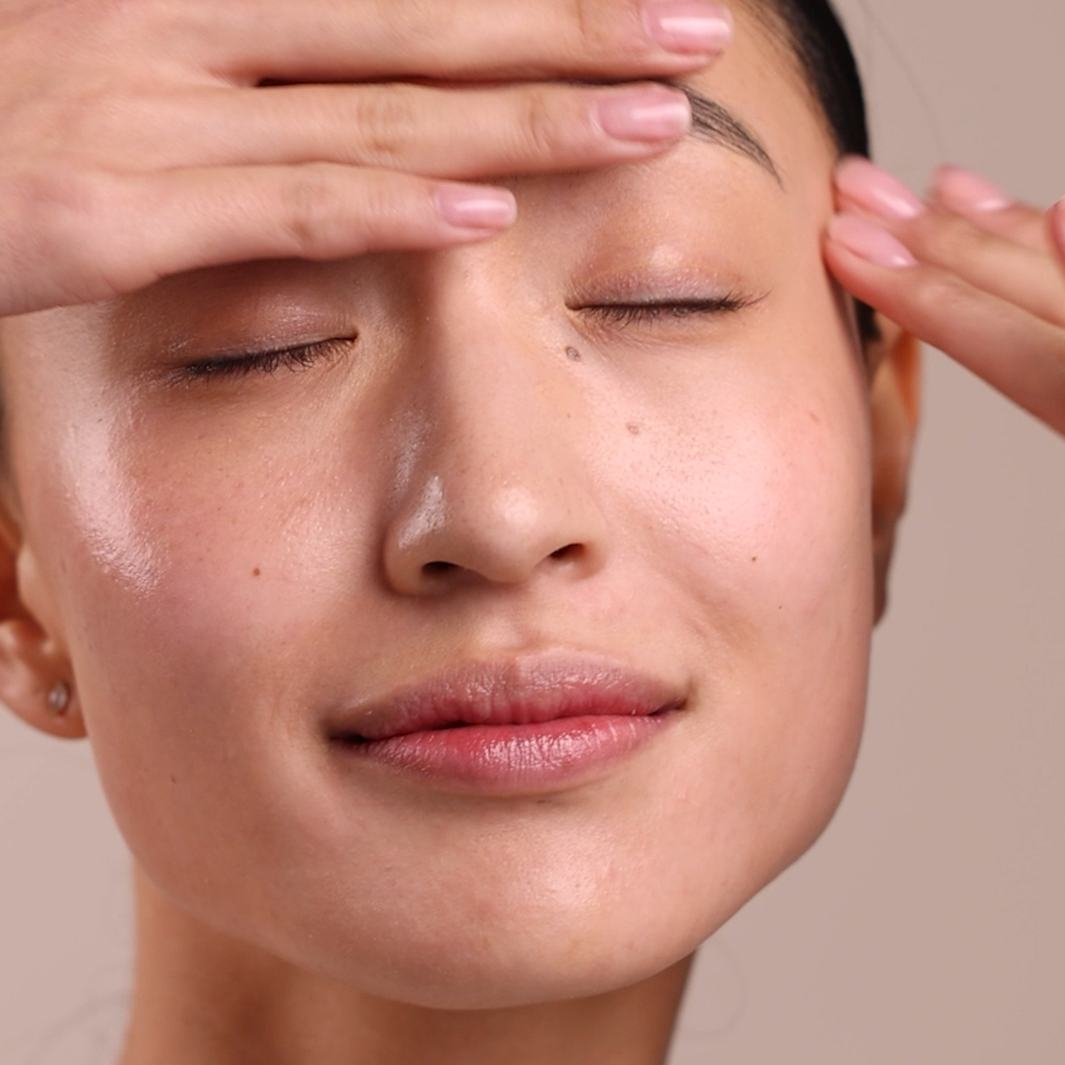 A woman applying the Eminence Organics Firm Skin Acai Moisturizer to her face