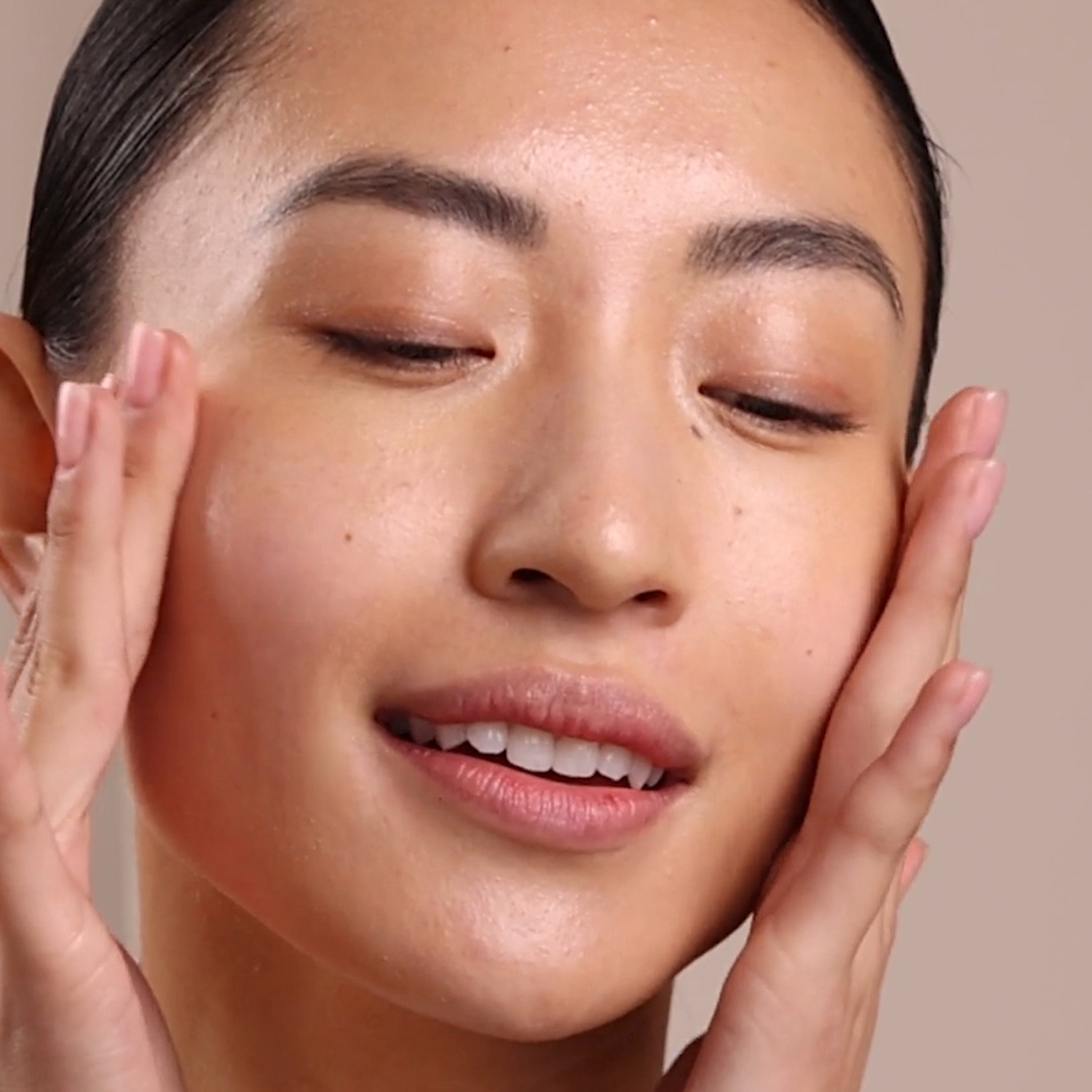 A woman applying the Eminence Organics Firm Skin Acai Booster-Serum to her face