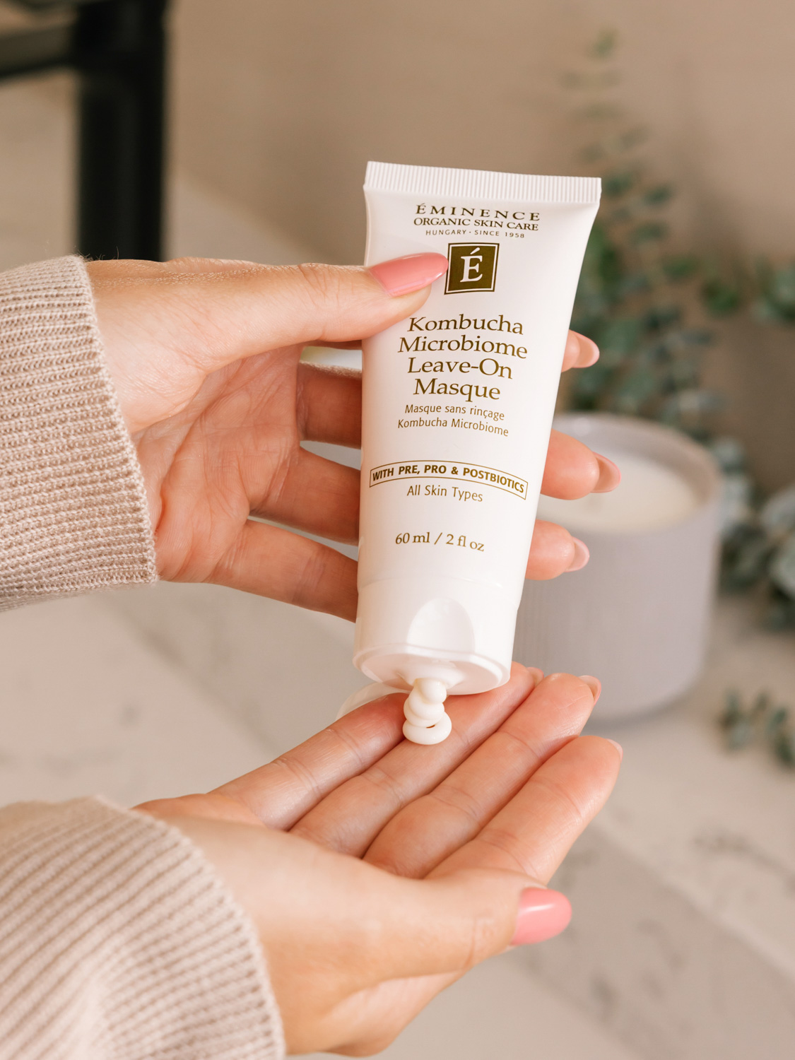 A woman applying the Eminence Organics Kombucha Microbiome Leave-On Masque on her fingertips