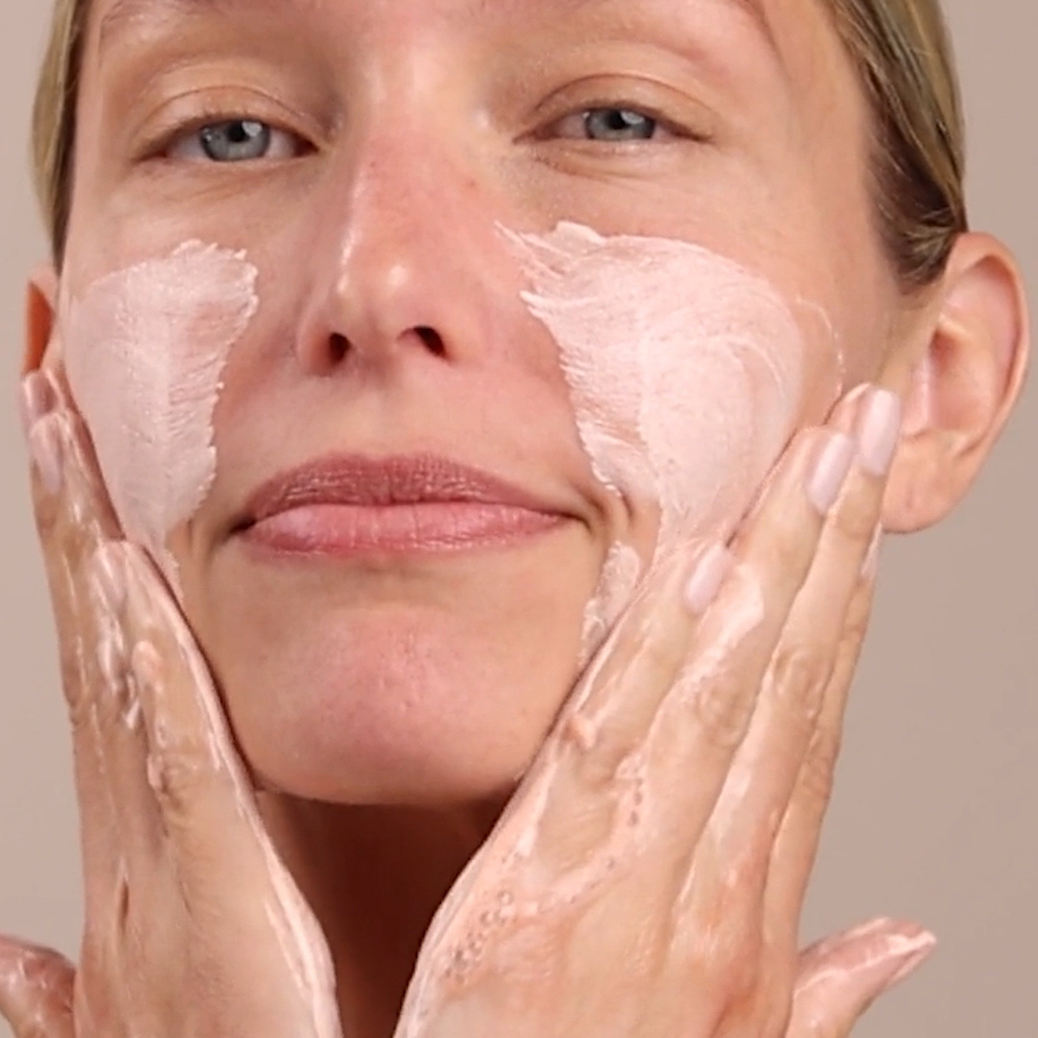 A woman applying Eminence Organics Barbados Cherry Enzyme Cleansing Powder to face
