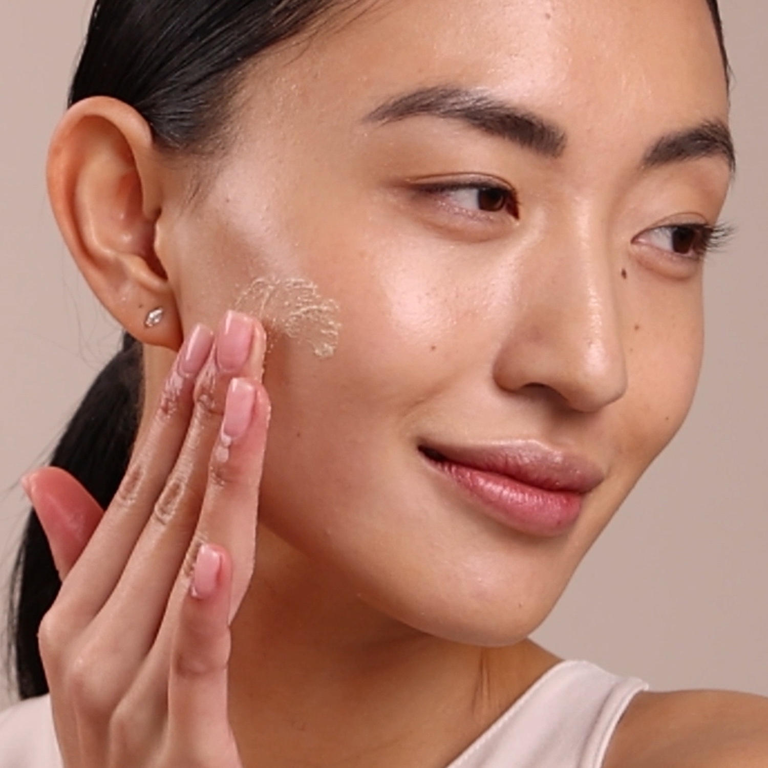 A woman applying the Eminence Organics Strawberry Rhubarb Dermafoliant on her face