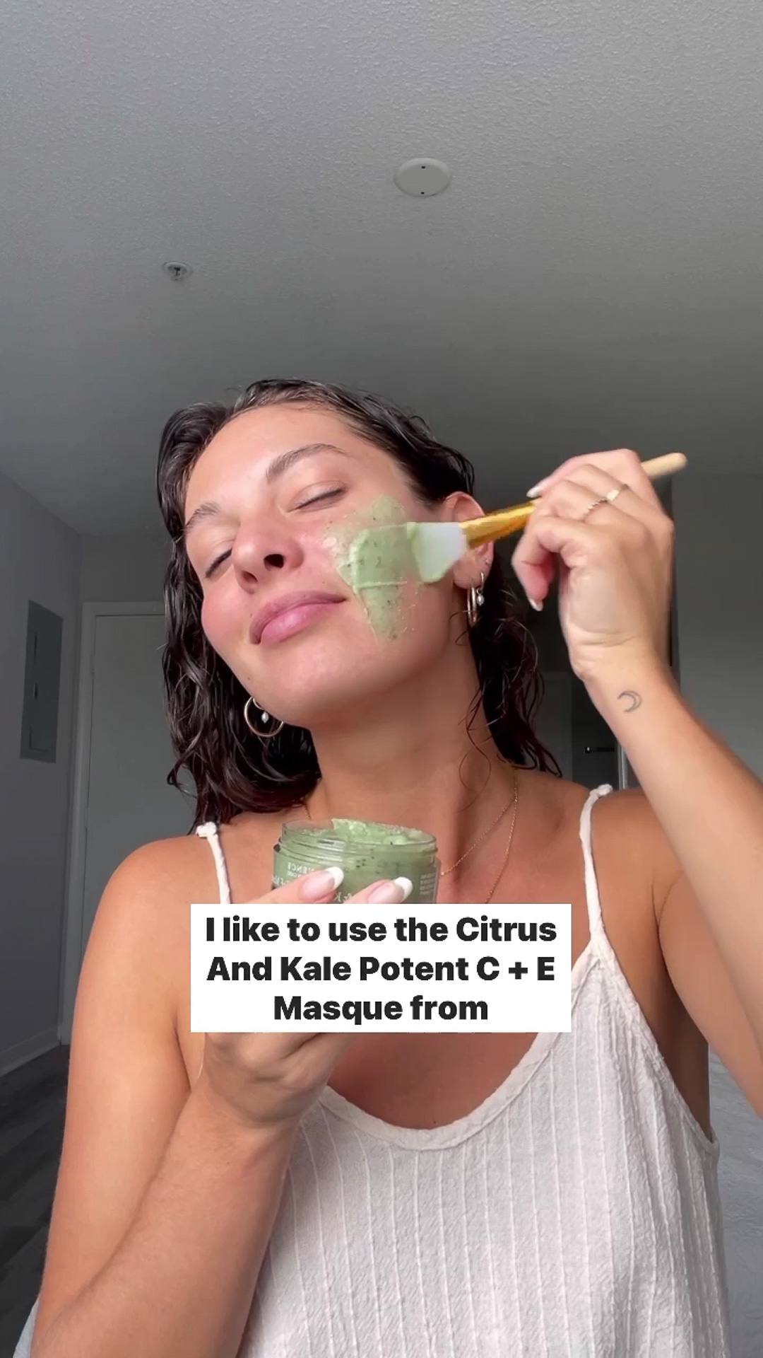 A woman applying Eminence Organics Citrus & Kale Potent C+E Serum to the face