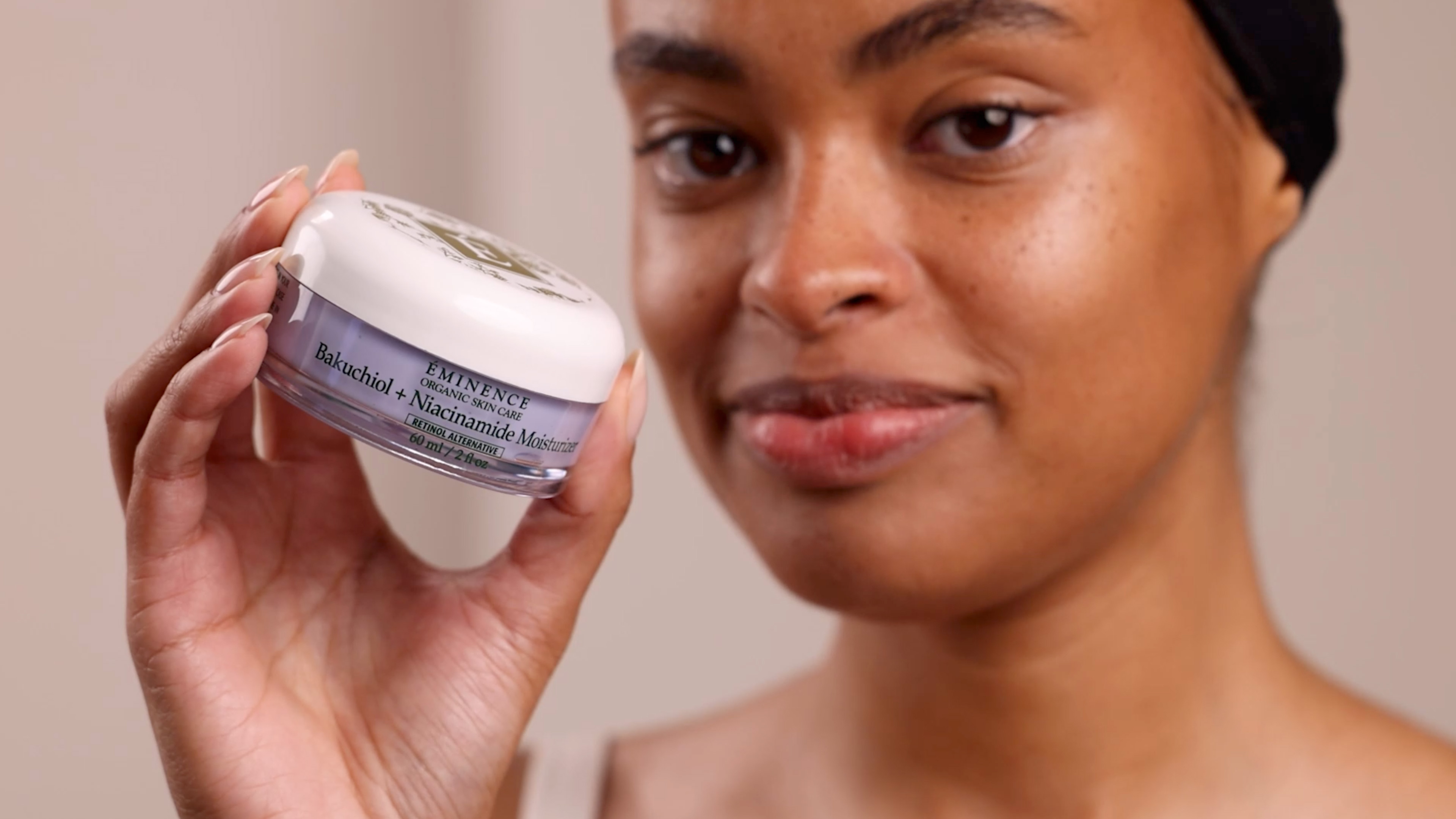 A woman holding Eminence Organics Bakuchiol + Niacinamide Moisturizer 