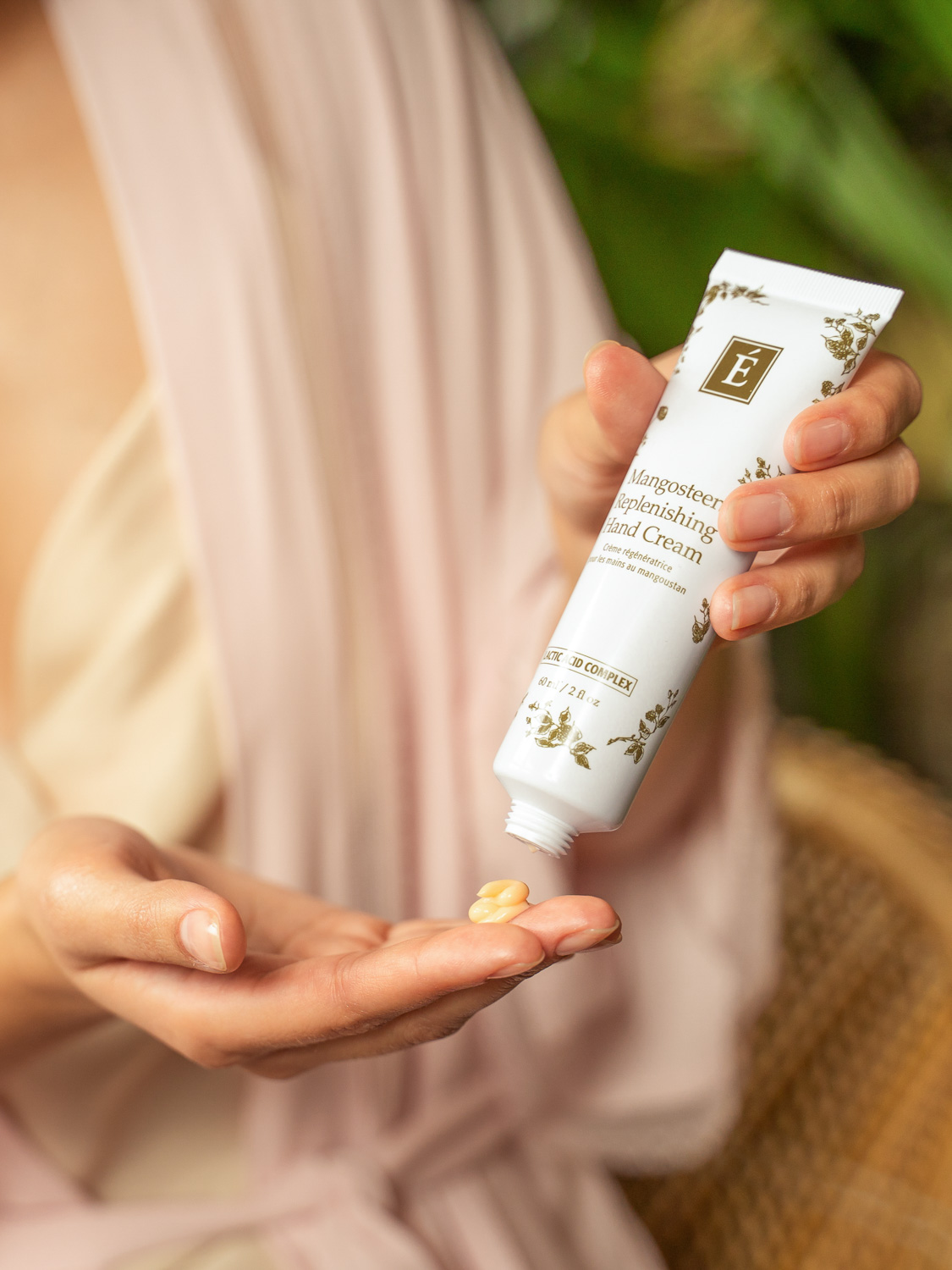 A woman applying the Eminence Organics Mangosteen Replenishing Hand Cream onto her hand