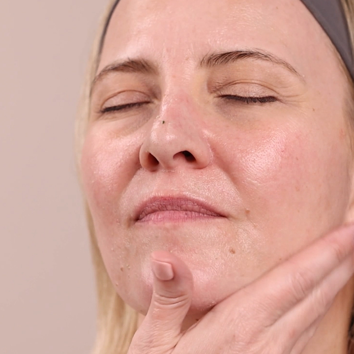 A woman applying Eminence Organics Citrus & Kale Potent C+E Serum to face