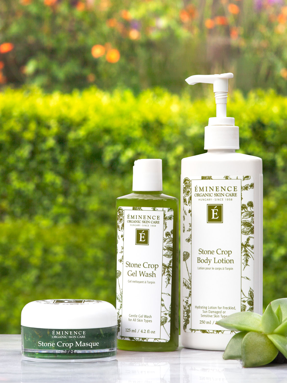 Eminence Organics Stone Crop Masque next to other Eminence Organics products with a green outdoors background