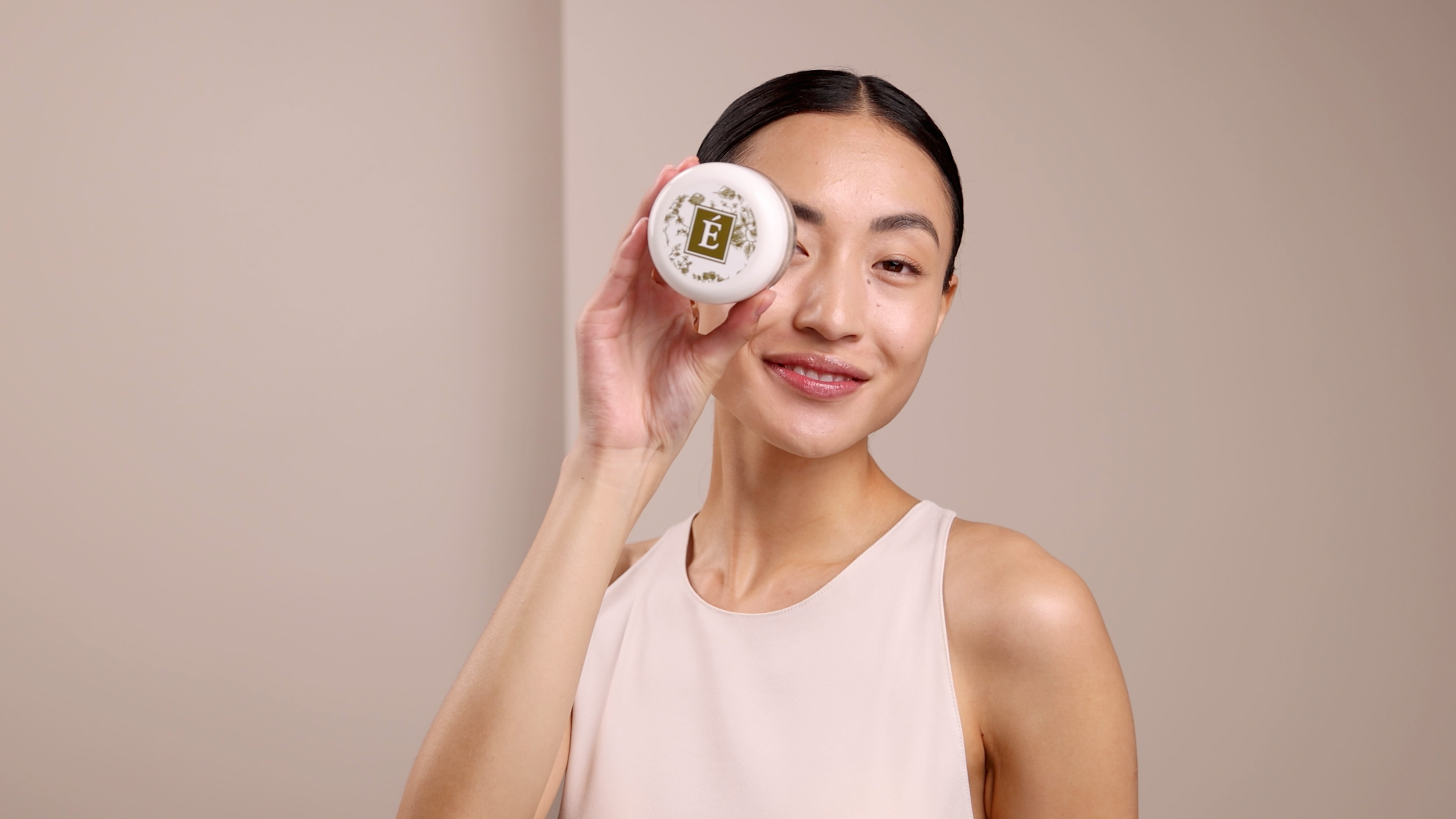 A woman holding Eminence Organics Bamboo Age Corrective Masque