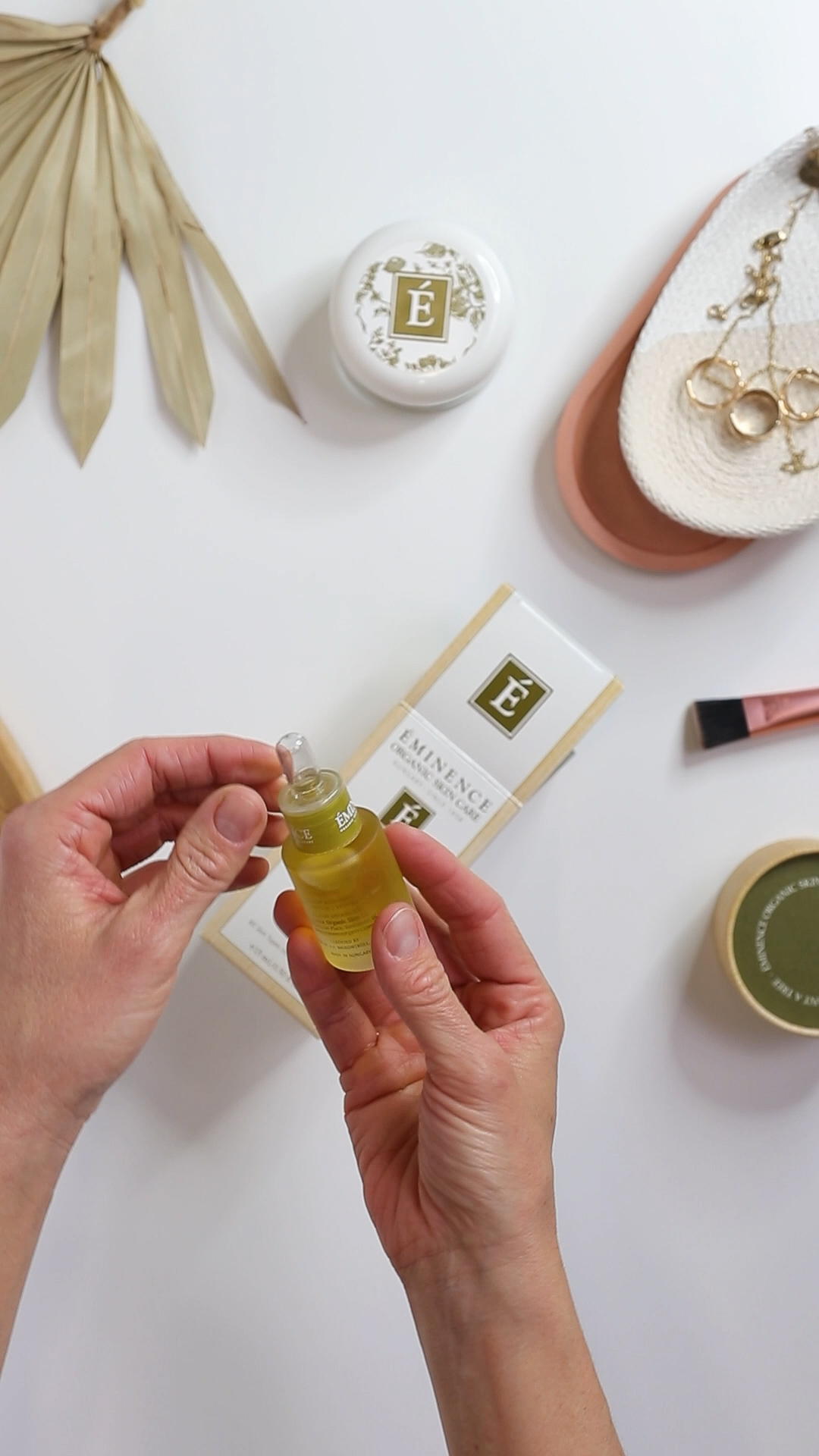 Two hands holding the Eminence Organics Facial Recovery Oil