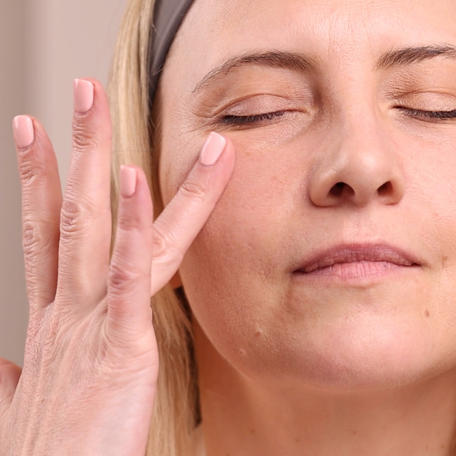 A woman applying the Eminence Organics Marine Flower Peptide Eye Cream to the eye area