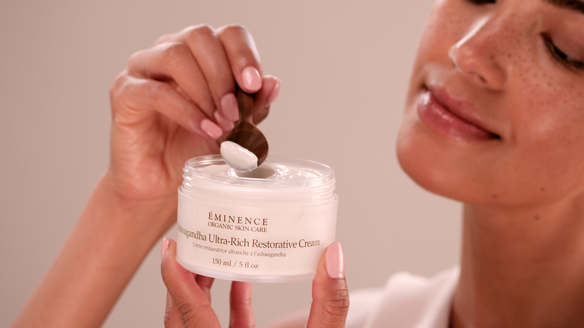 A woman holding the Eminence Organics Ashwagandha Ultra-Rich Restorative Cream 