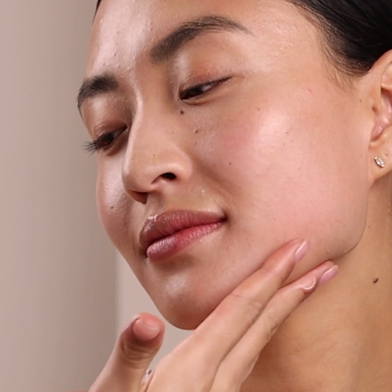 A woman applying the Eminence Organics Marine Flower Peptide Night Cream to her jaw and neck