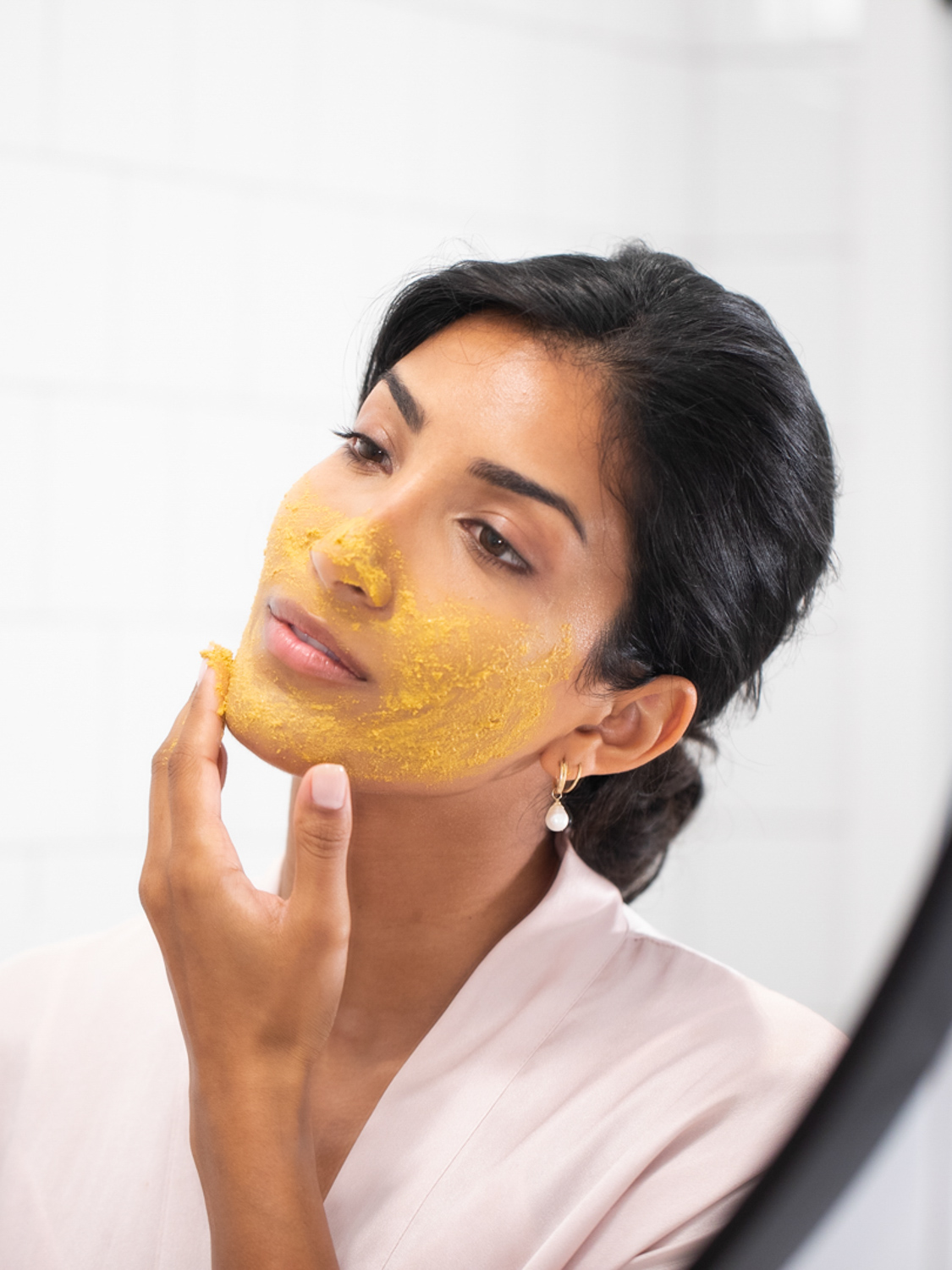 A woman with the Eminence Organics Turmeric Energizing Treatment applied onto her face