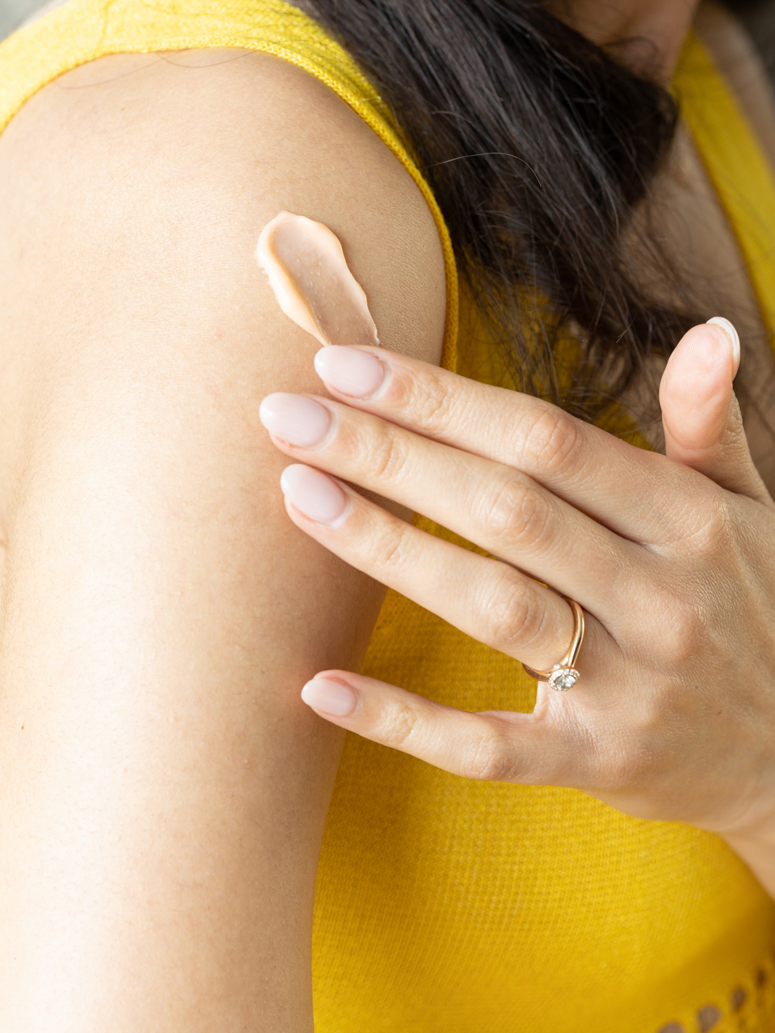 A woman applying the Eminence Organics Stone Crop Contouring Body Cream on her arm
