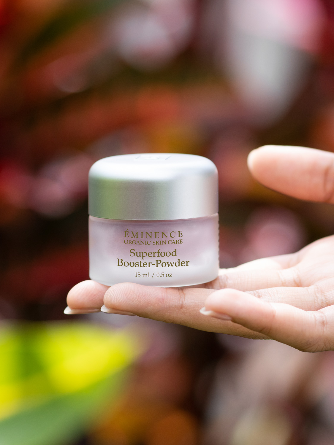 A hand holding the Eminence Organics Superfood Booster-Powder
