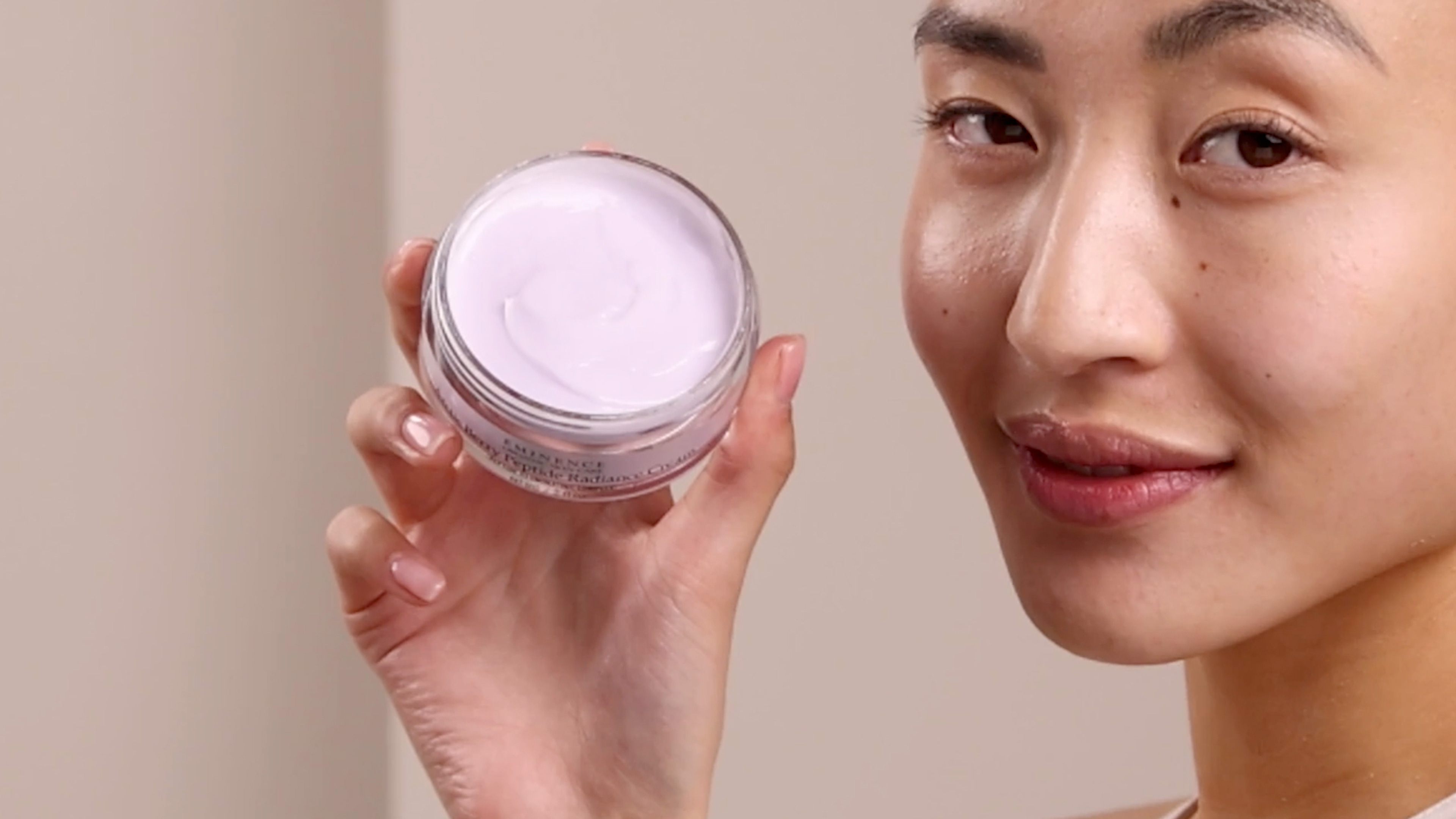 A woman holding Eminence Organics Arctic Berry Radiance Cream