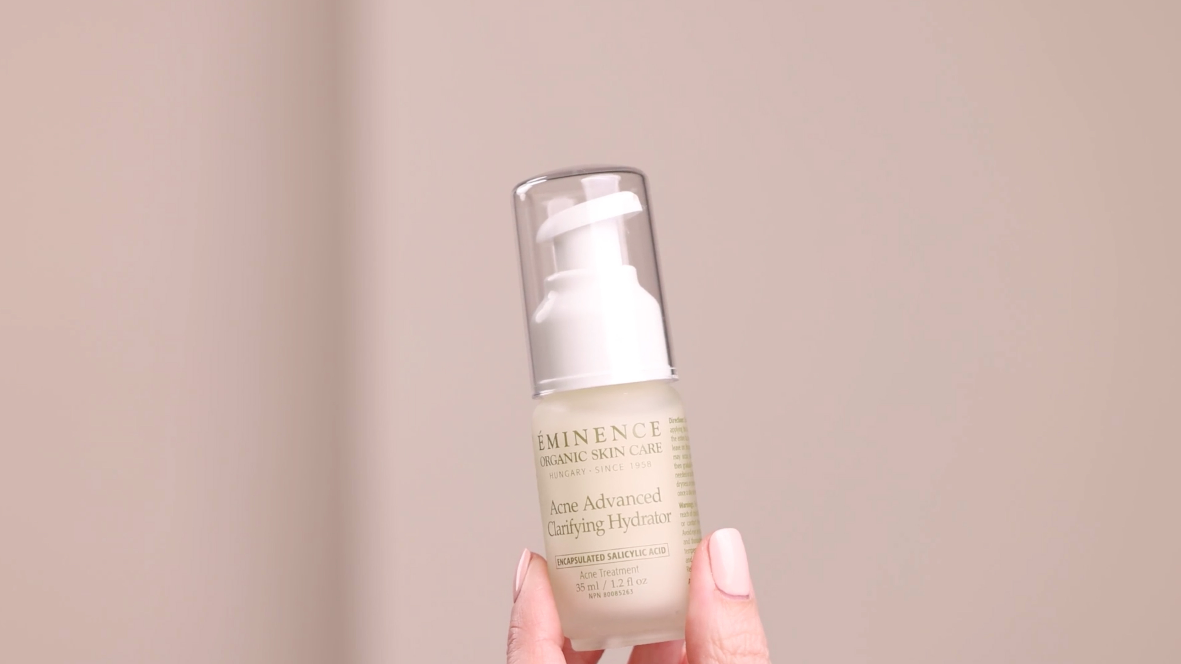 A woman holding Eminence Organics Acne Advanced Clarifying Hydrator