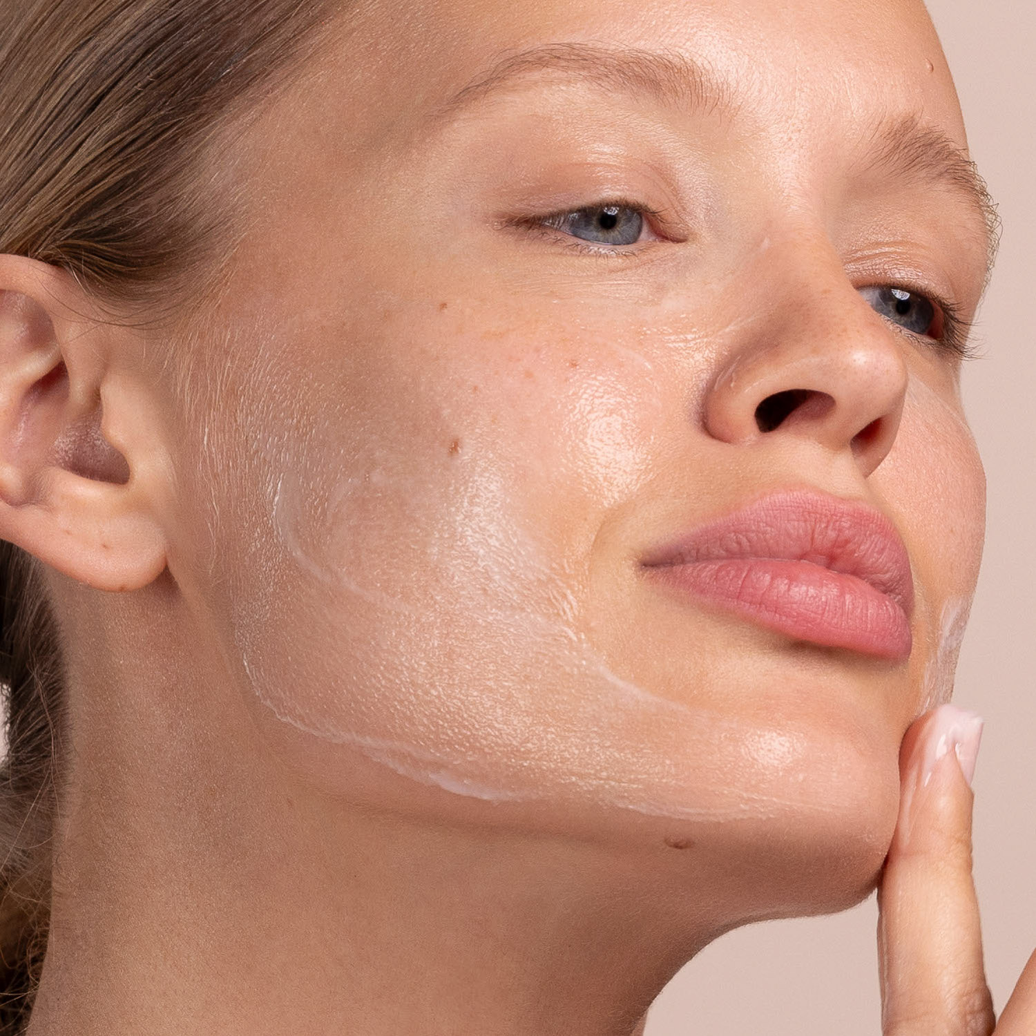 A woman applying the Eminence Organics Lemon Grass Cleanser on her face