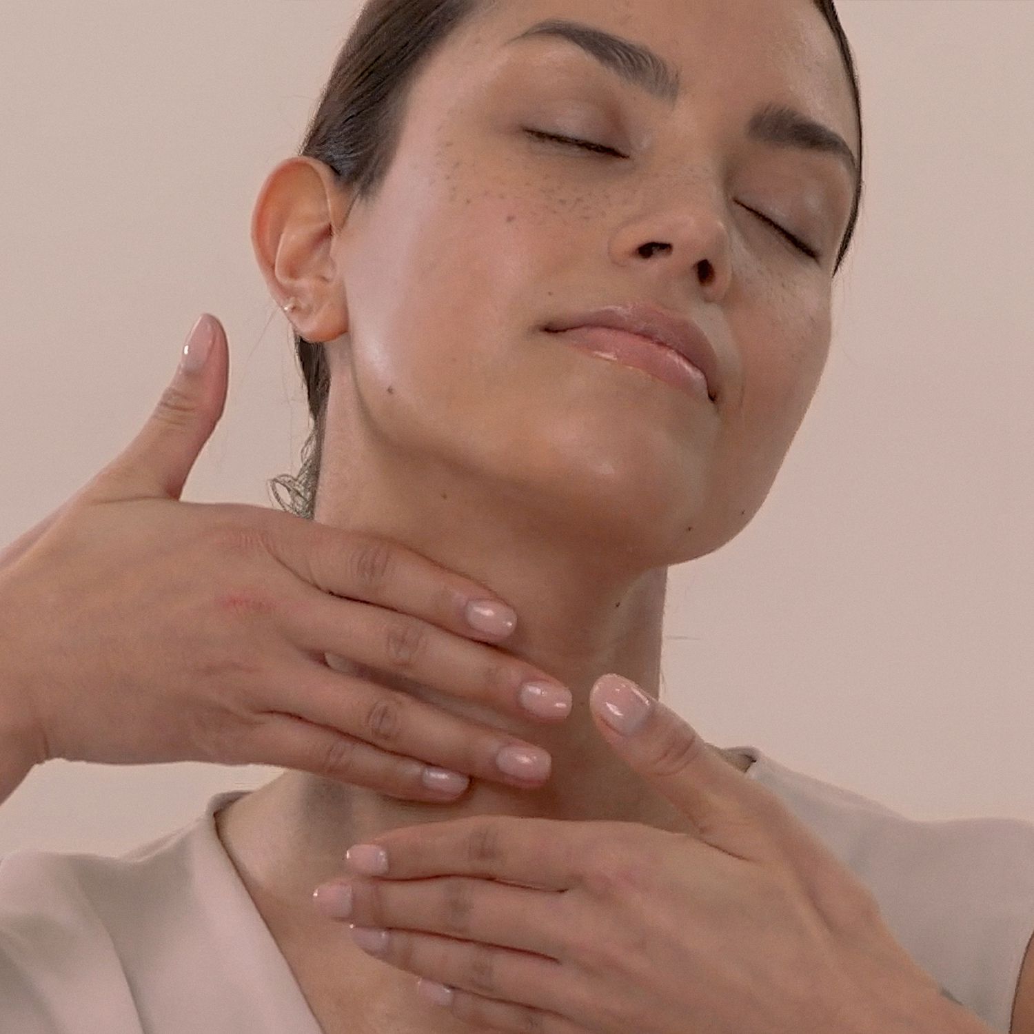 A woman applying the Eminence Organics Hibiscus Ultra Lift Neck Cream onto the palm of her hand
