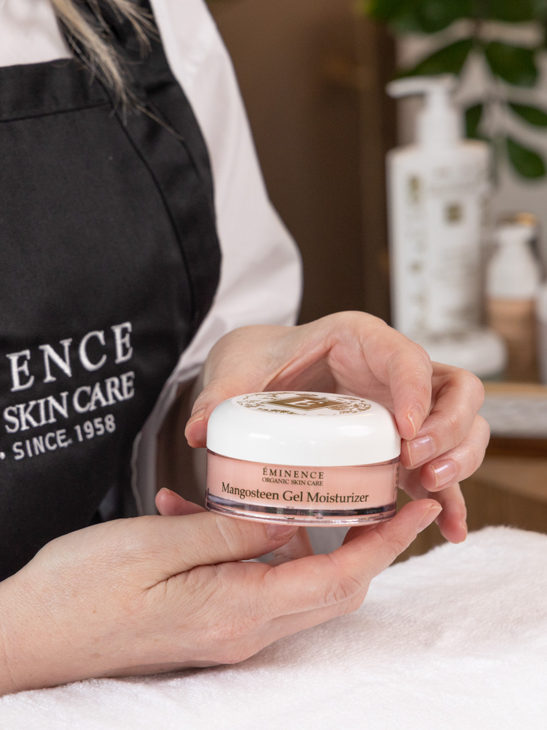 A close up of woman holding the Eminence Organics Mangosteen Gel Moisturizer Jar