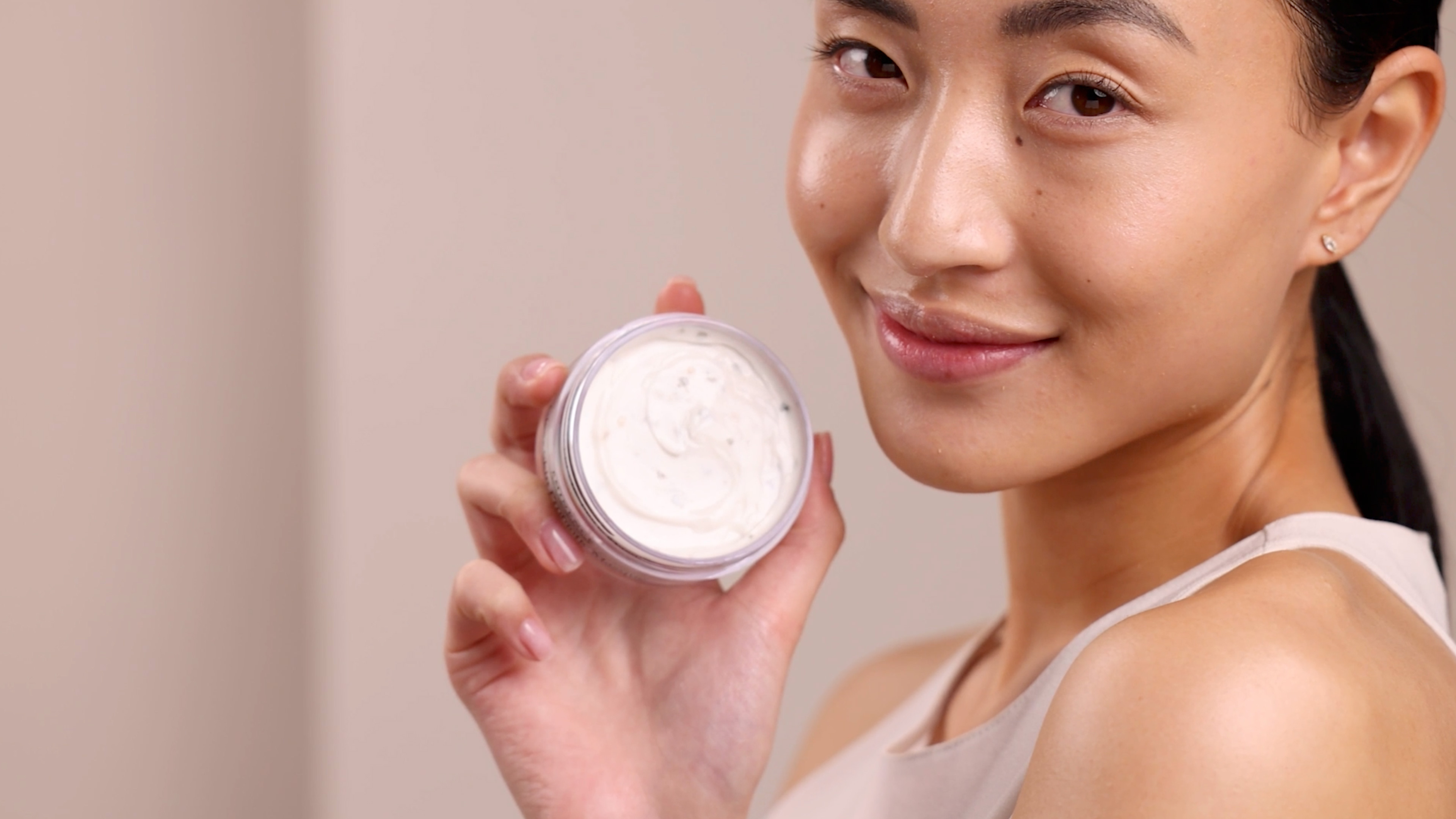A woman holding Eminence Organics Clear Skin Probiotic Masque