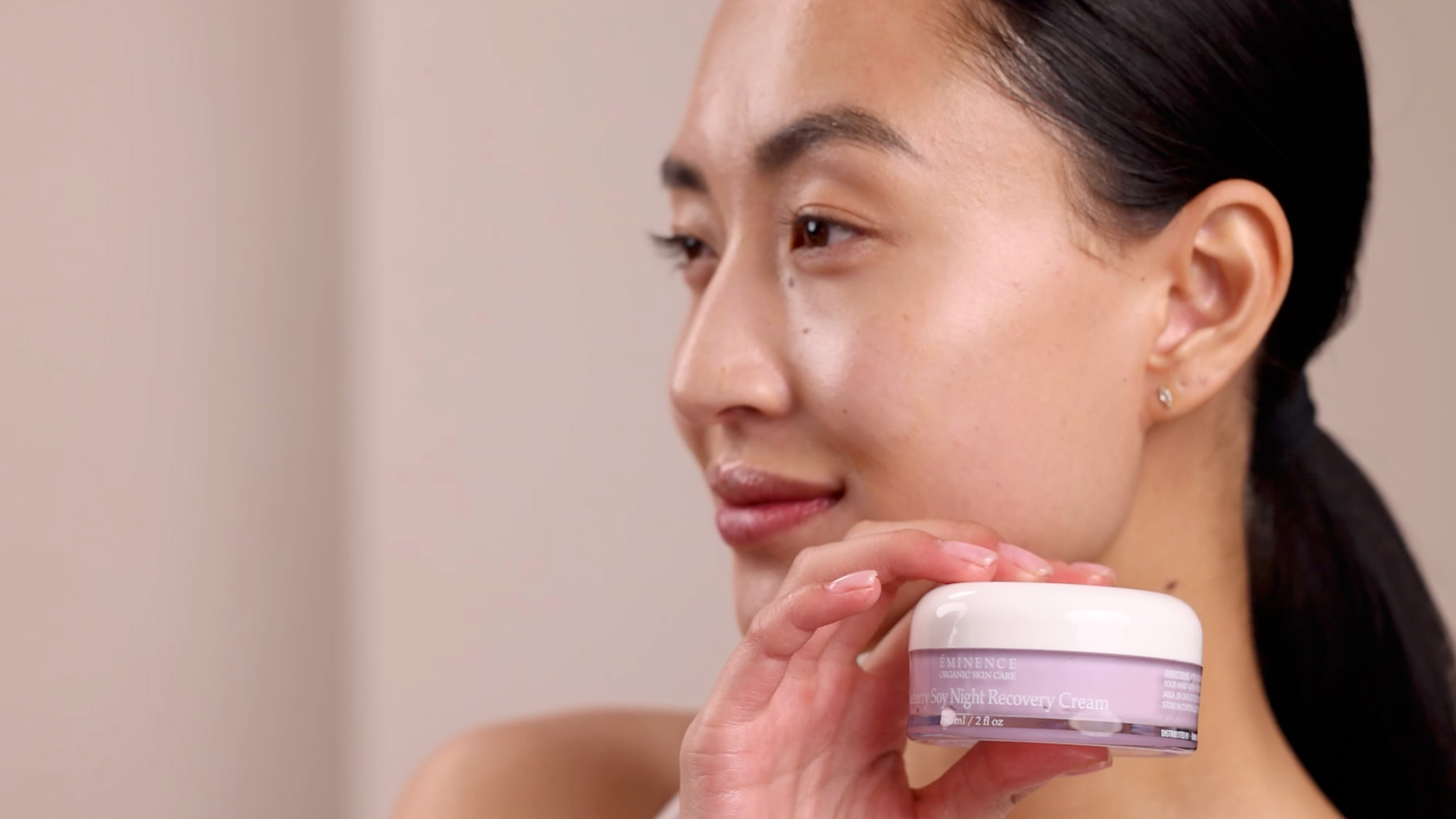 A woman holding Eminence Organics Blueberry Soy Night Recovery Cream