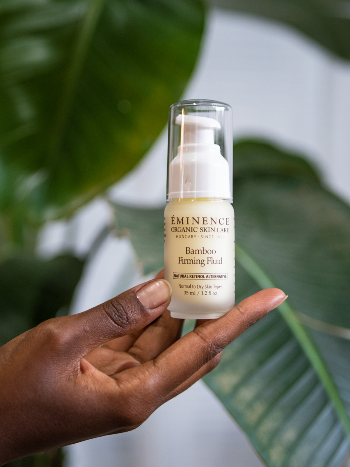 A hand holding Eminence Organics Bamboo Firming Fluid