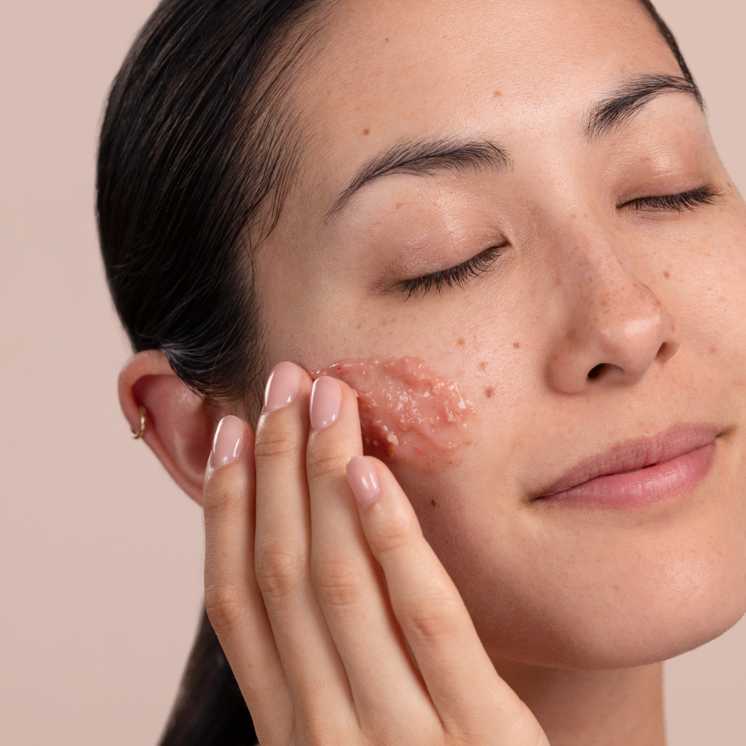 A woman with a swatch of the Eminence Organics Radish Seed Refining Peel on her face
