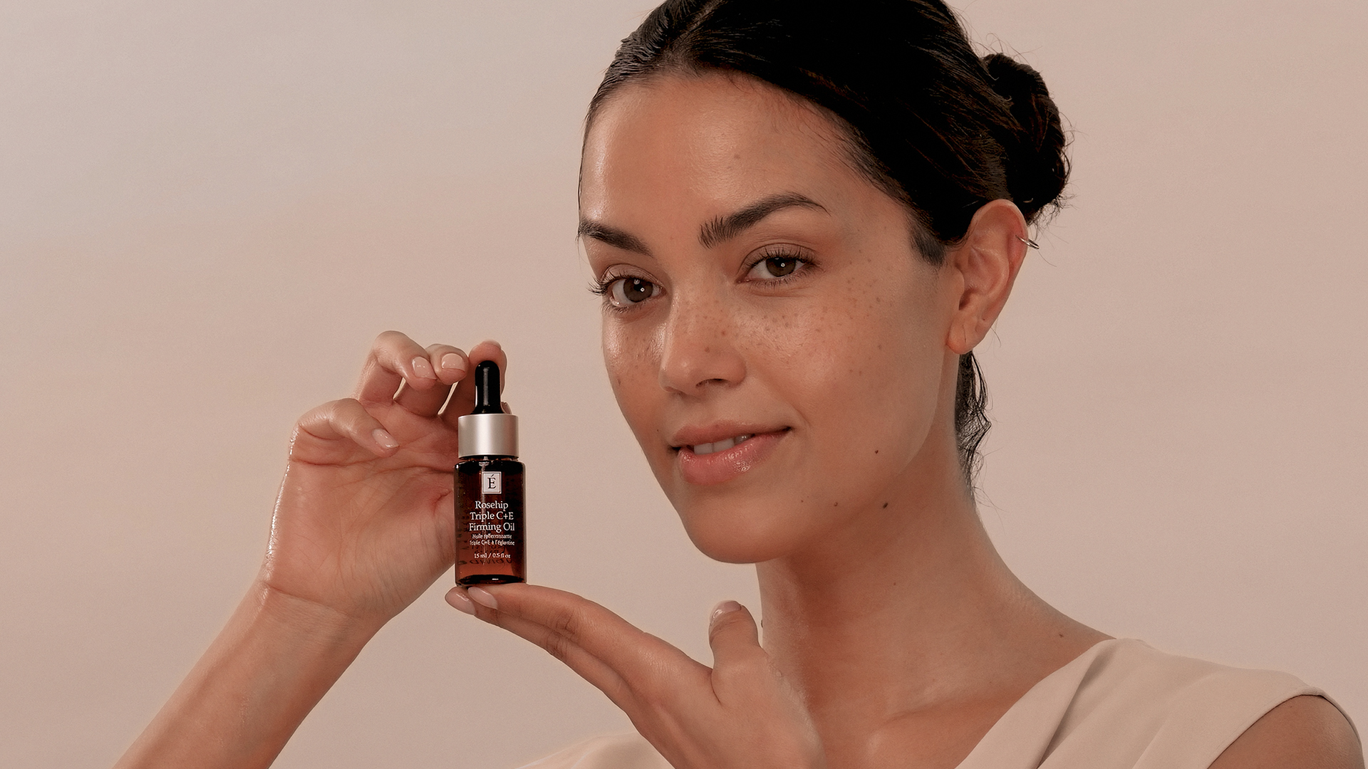 A woman holding the Eminence Organics Rosehip Triple C+E Firming Oil Mini