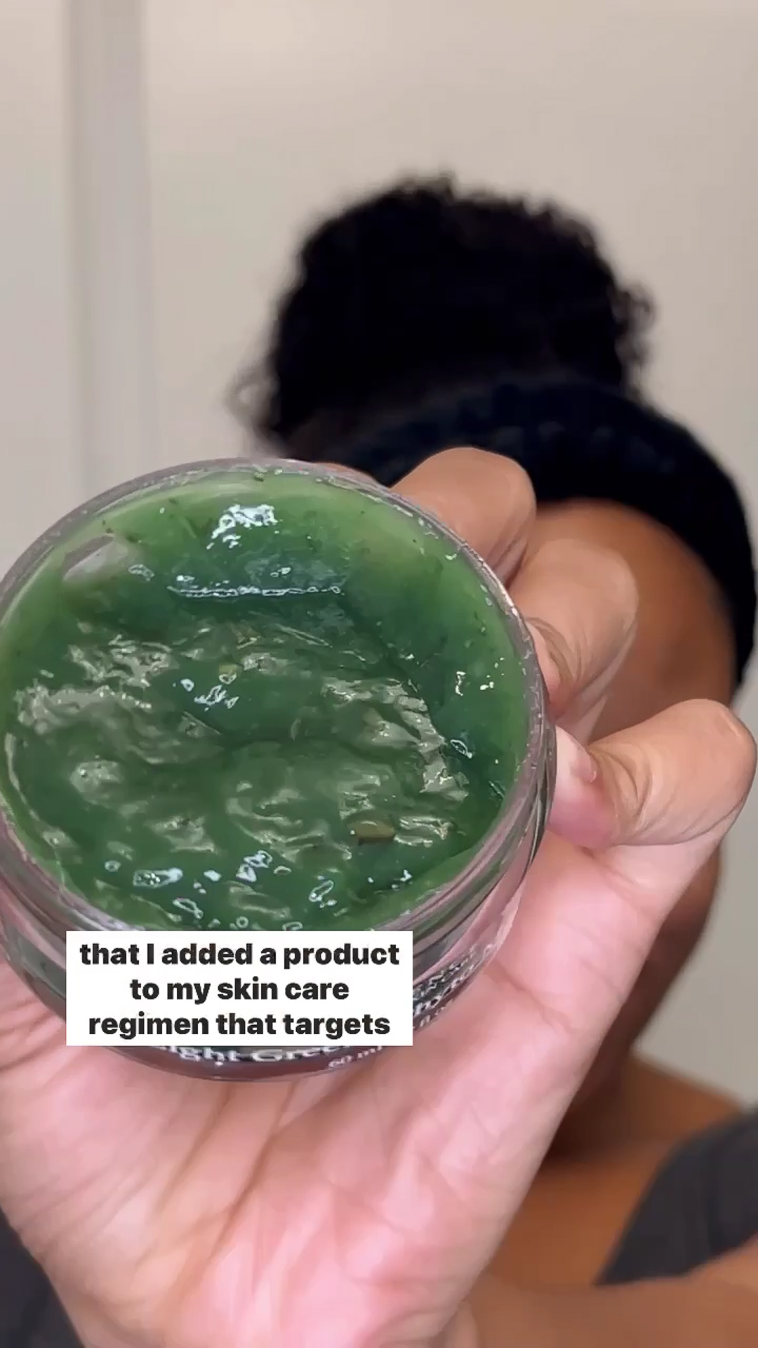 A person holding the Eminence Organics Eight Greens Phyto Masque – Not Hot up to the camera