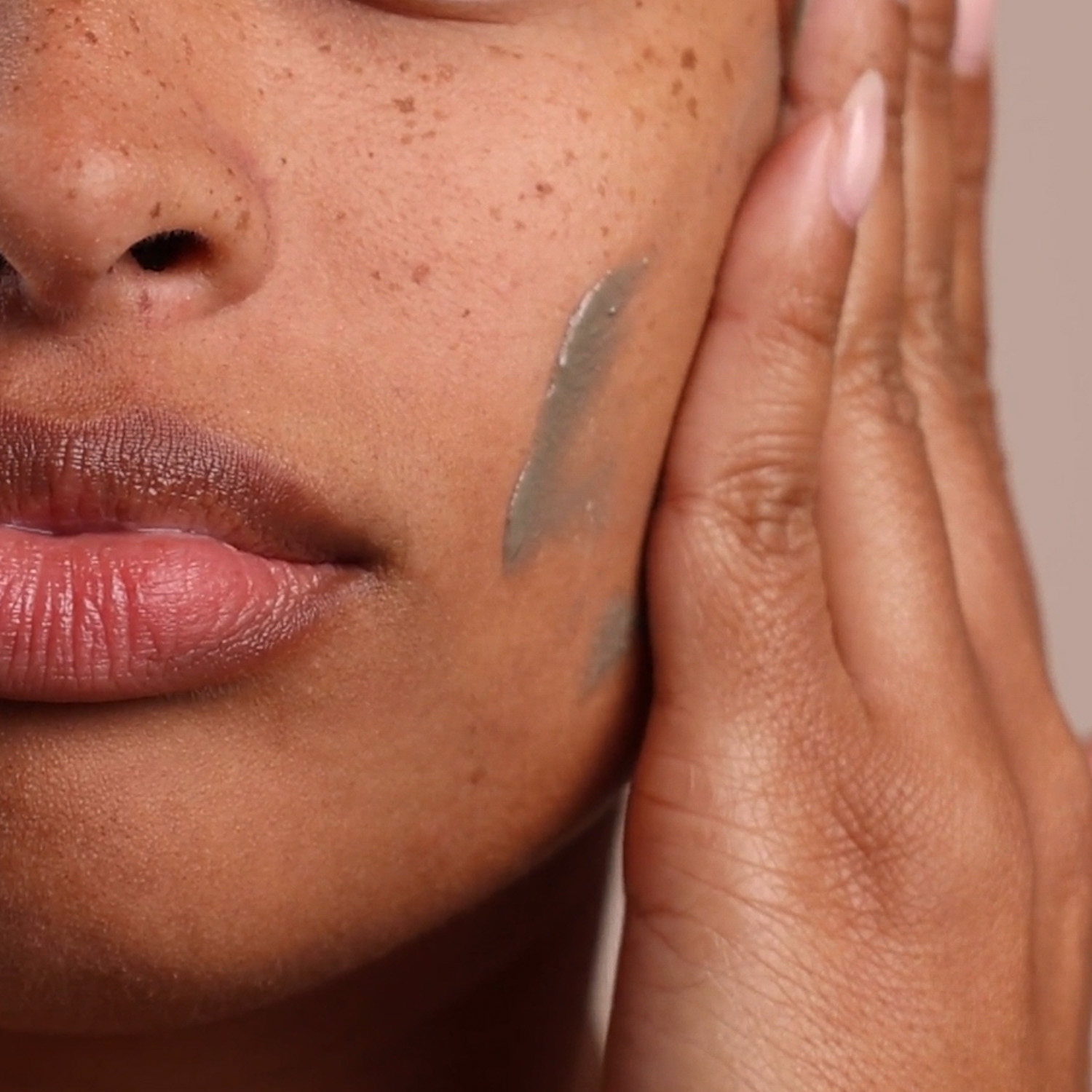 A woman applying Eminence Organics Charcoal & Black Seed Clay Masque to face