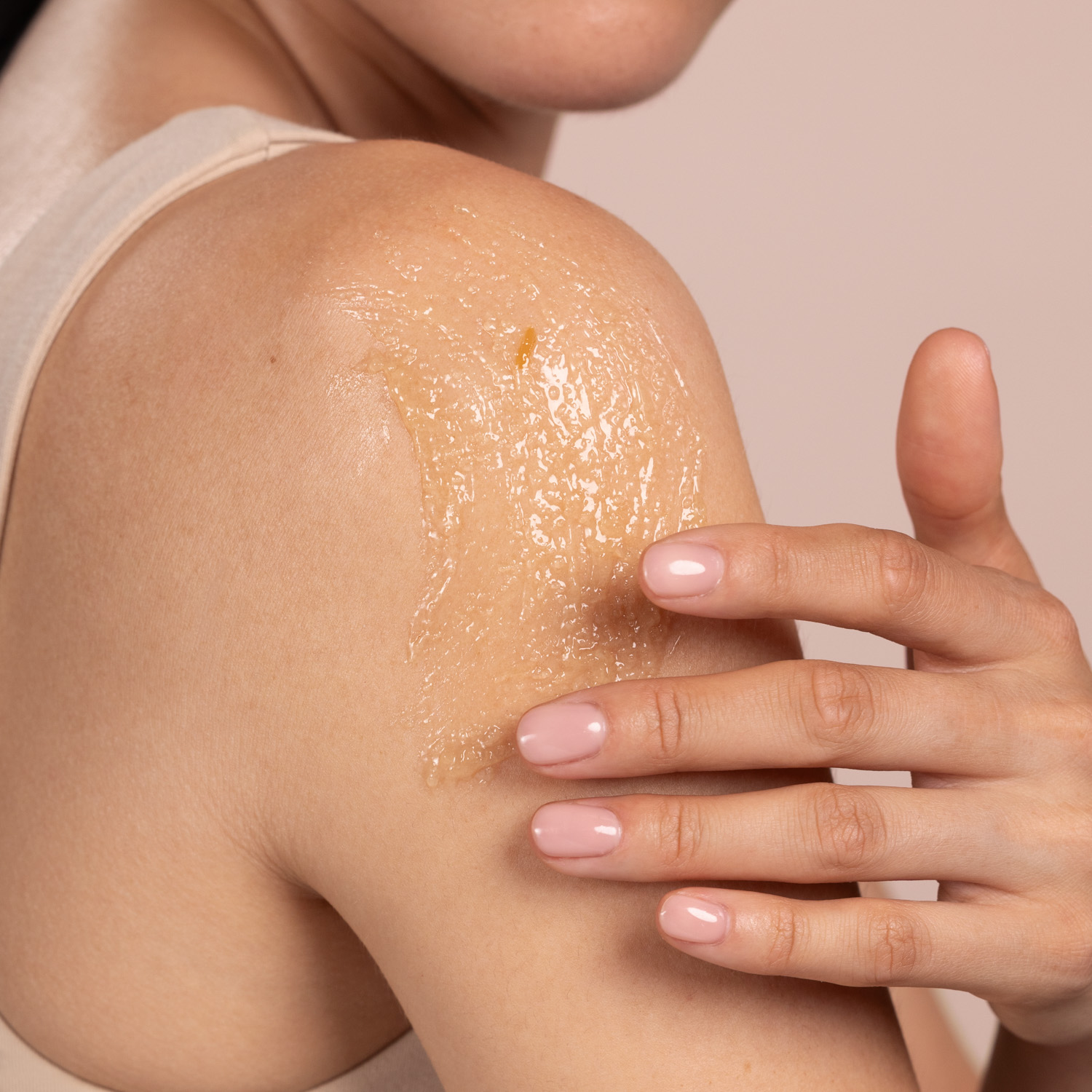 A woman applying the Eminence Organics Coconut Sugar Scrub on her shoulder