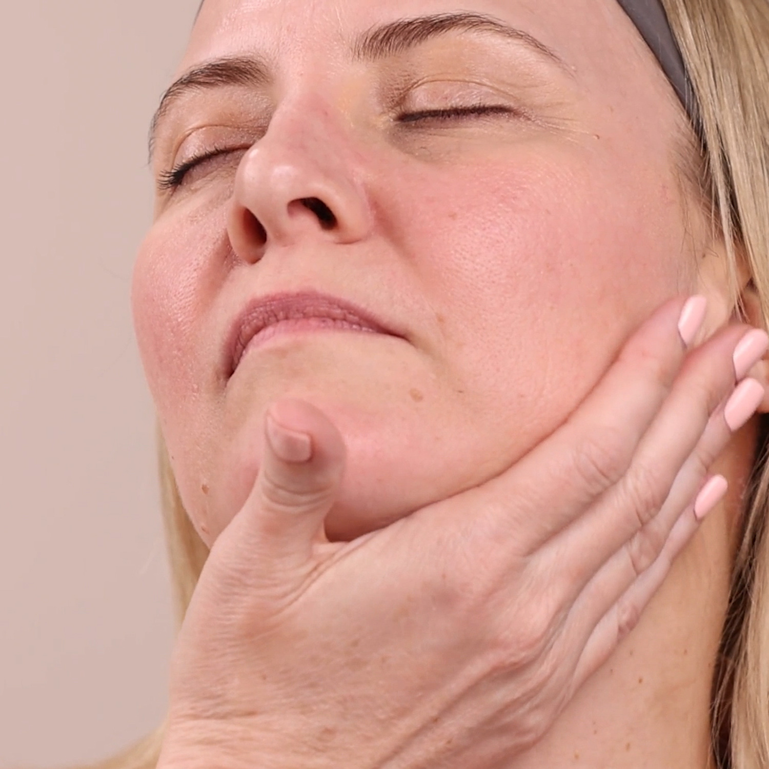 A close up of a woman applying the Eminence Organics Marine Flower Peptide Concentrate on her jaw and neck area