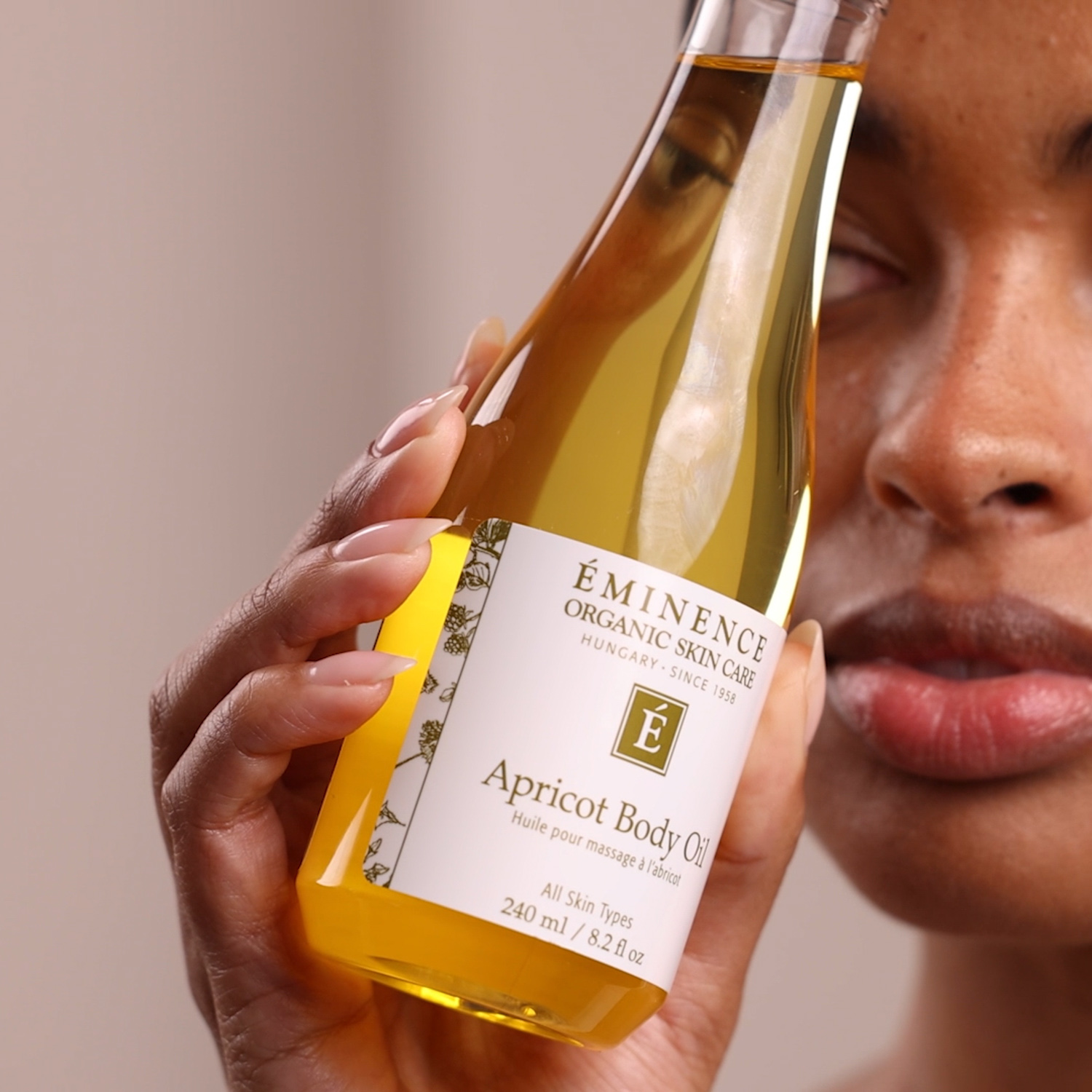 A woman holding Eminence Organics Apricot Body Oil